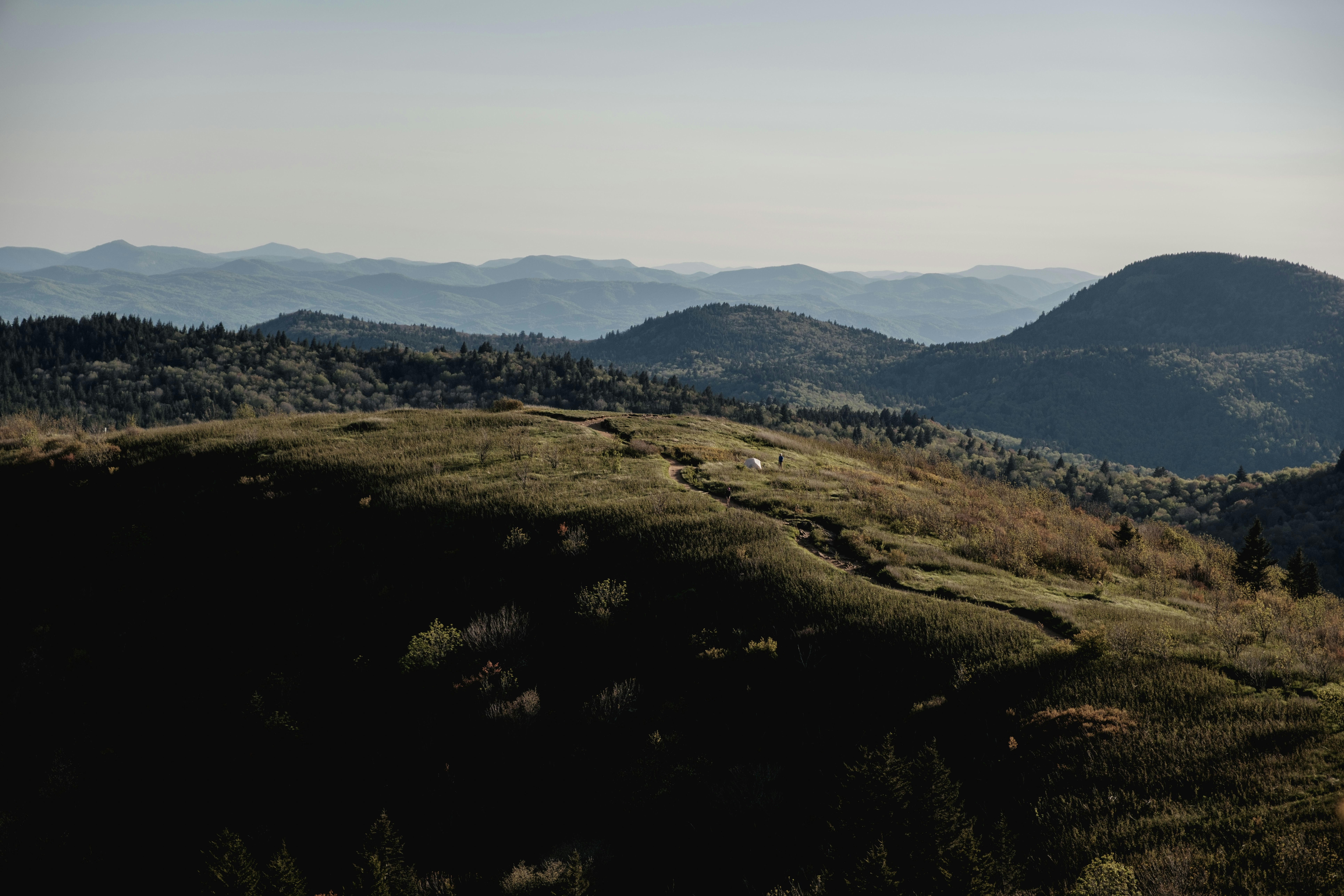 Rolling hills and layered mountains under clear sky