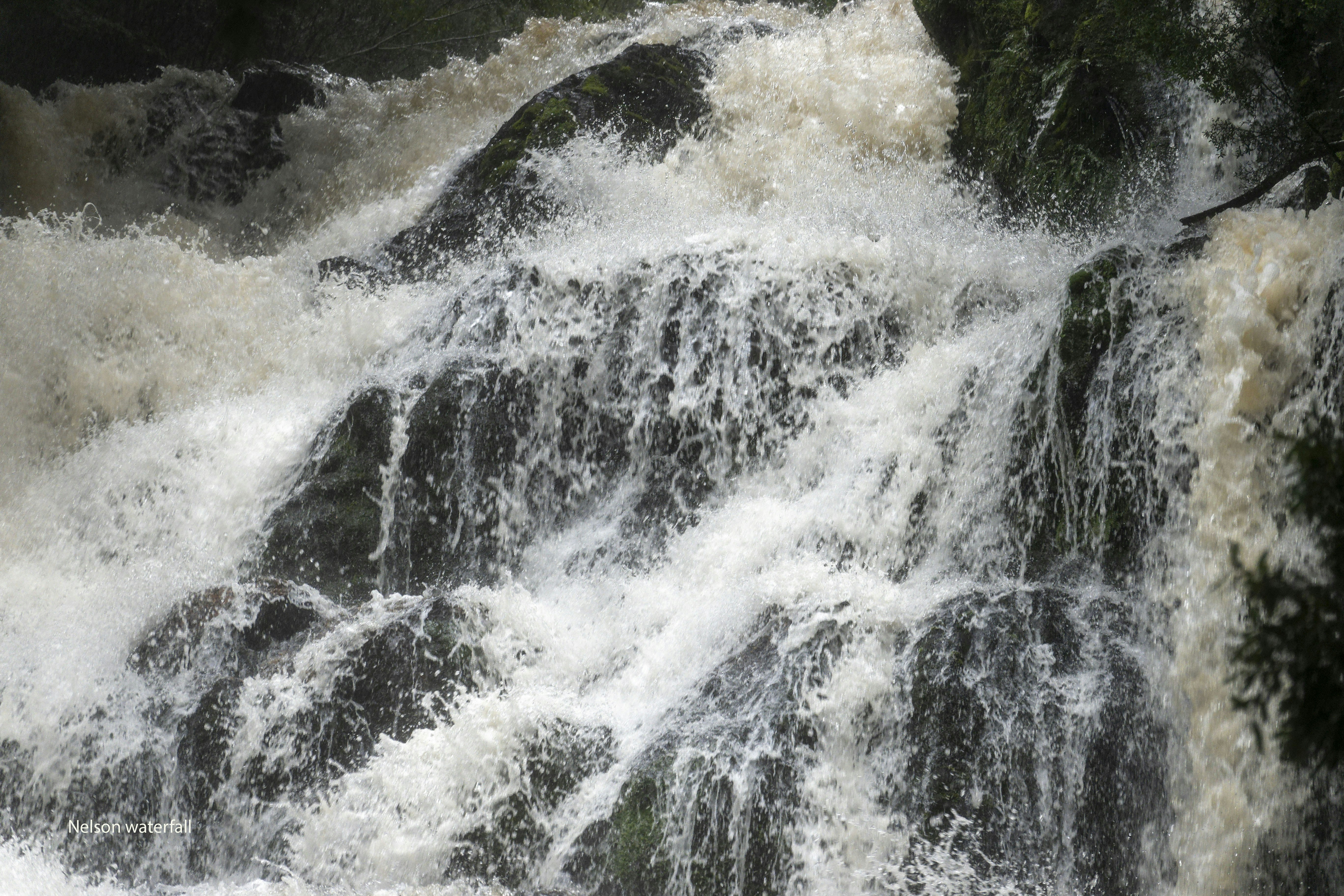 White water cascades over dark rocks in a powerful waterfall