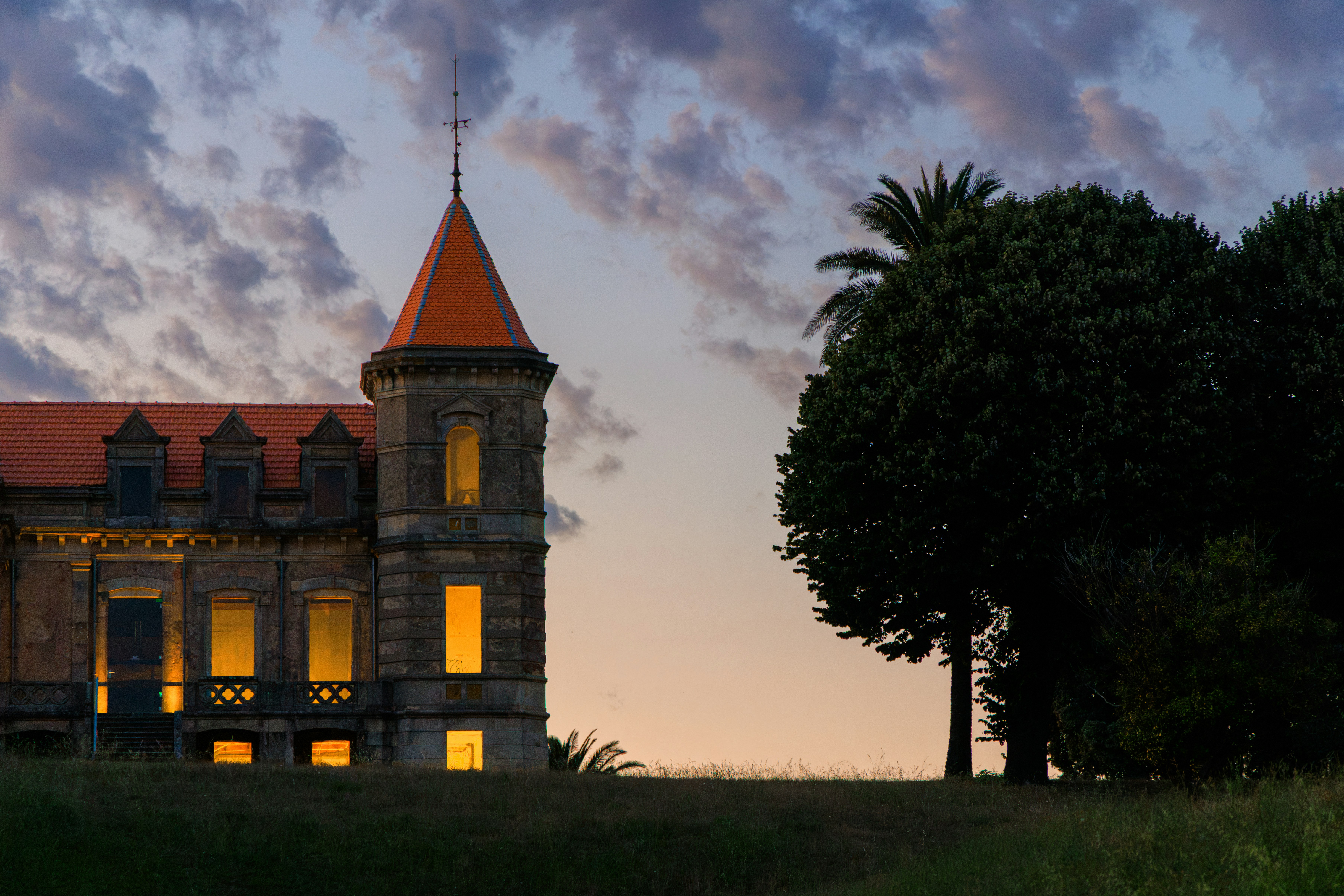 A historic castle with illuminated windows at twilight.