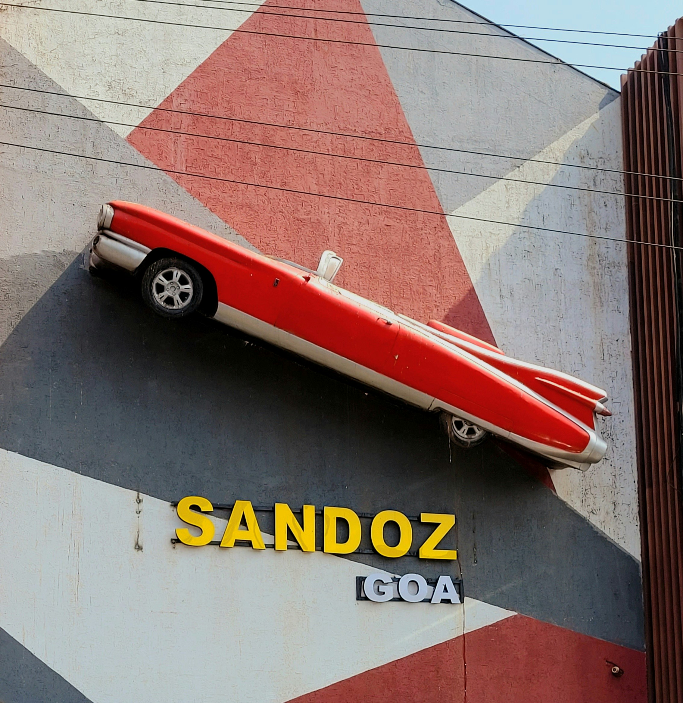 Red vintage car mounted on a geometric patterned building wall