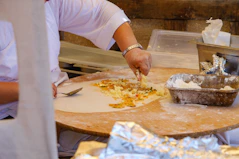 Preparing savory flatbread with cheese on a wooden board.