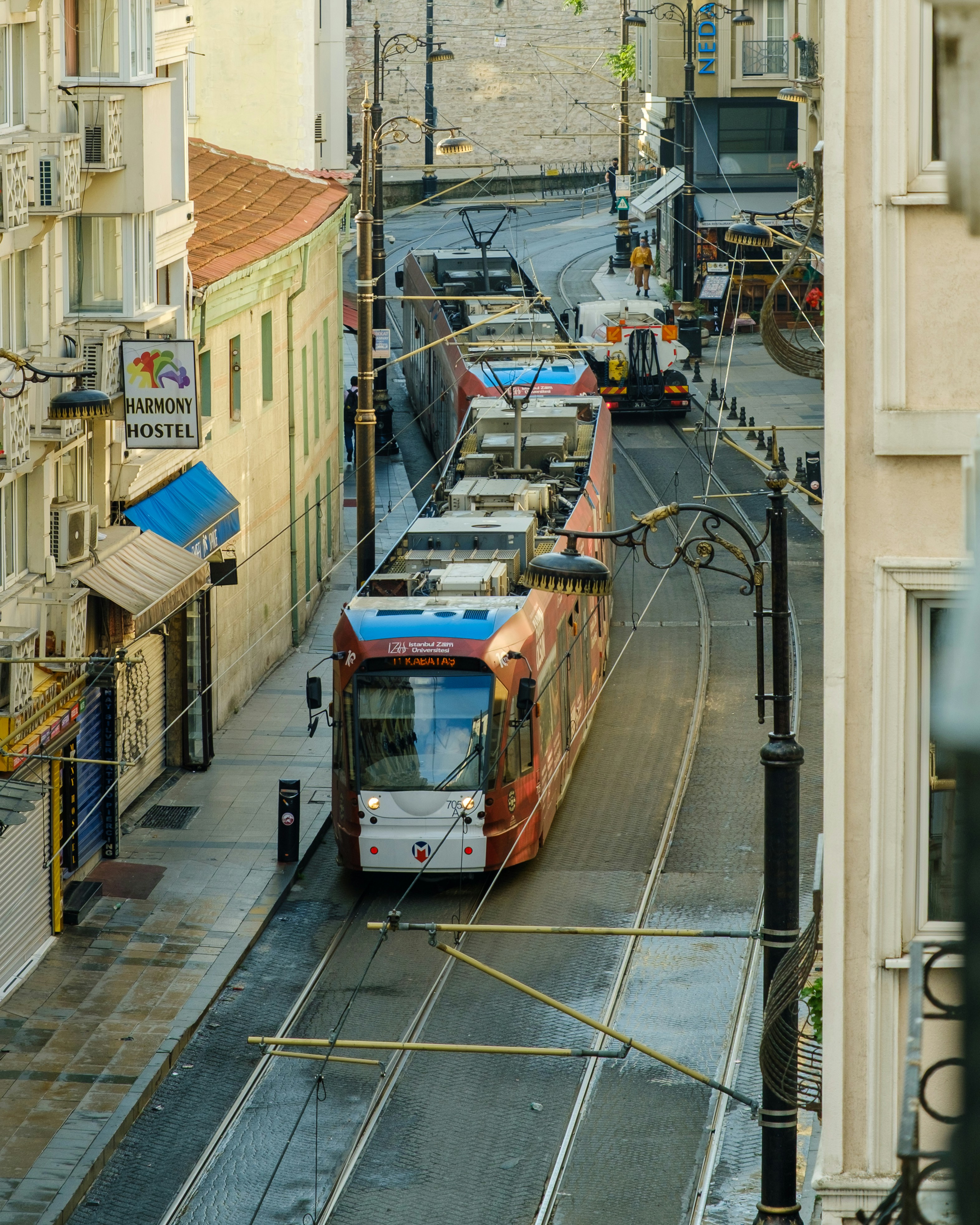A red and blue tram on city street tracks.
