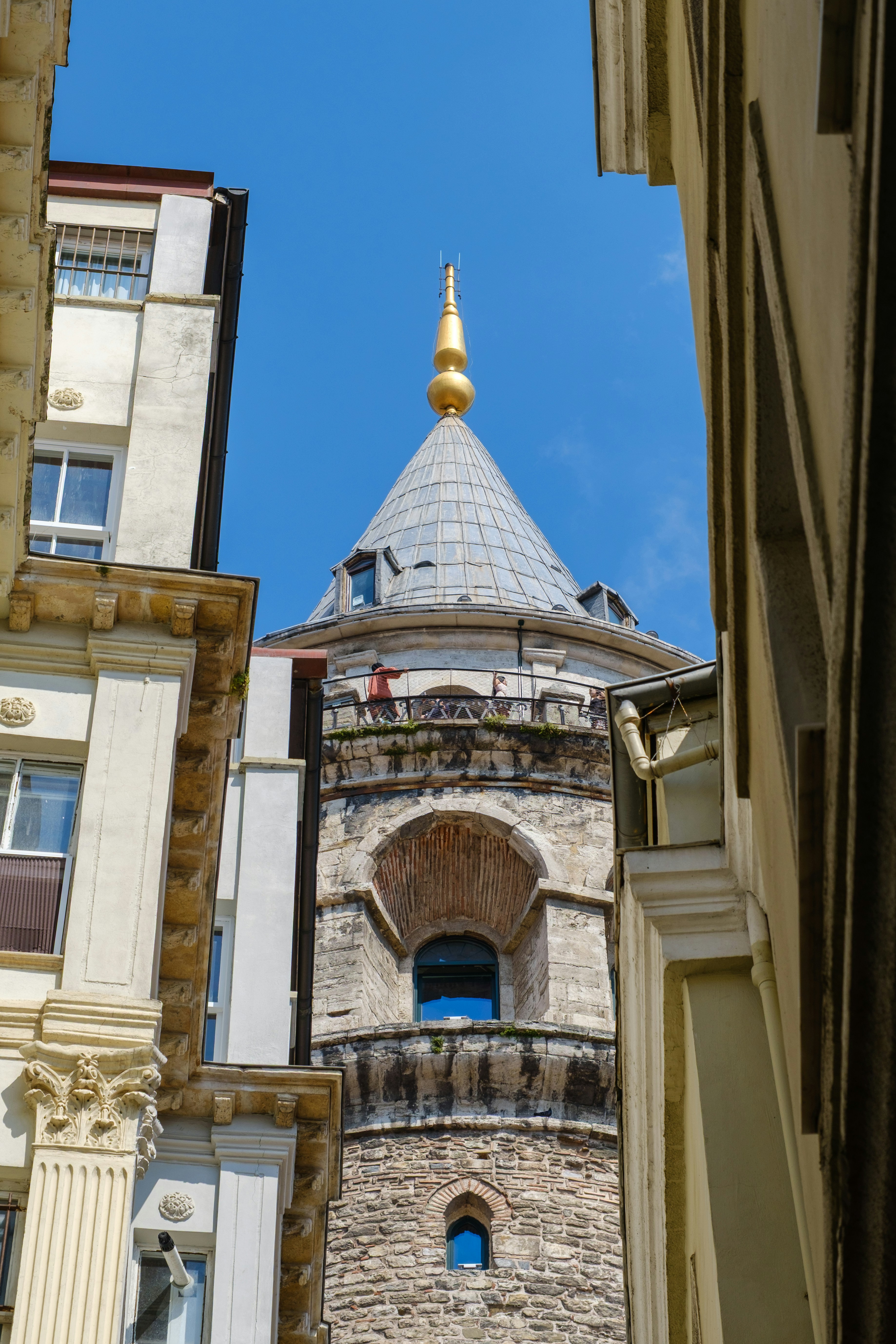 The galata tower framed by buildings against a blue sky.