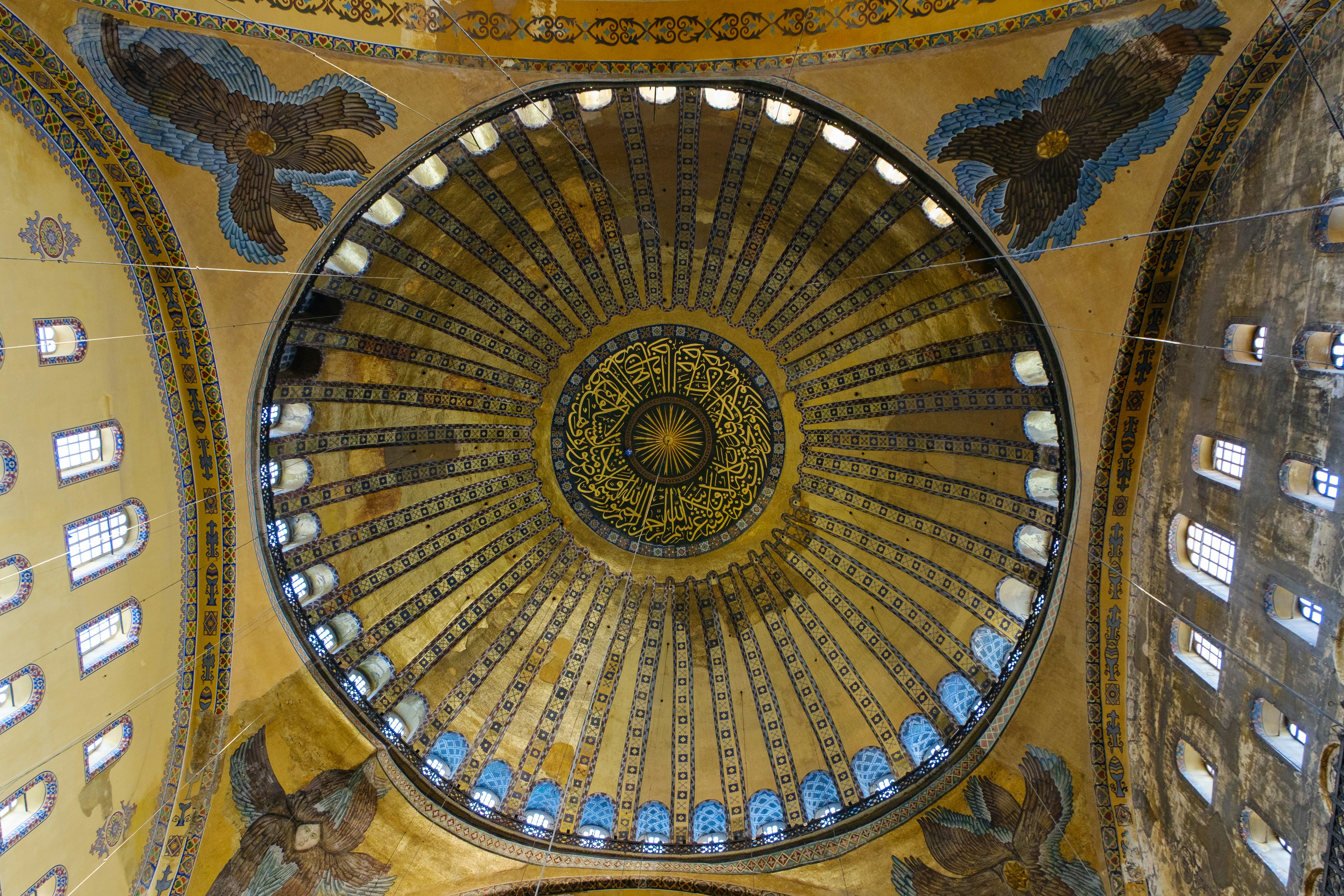 Grand dome interior with golden mosaics and arched windows.