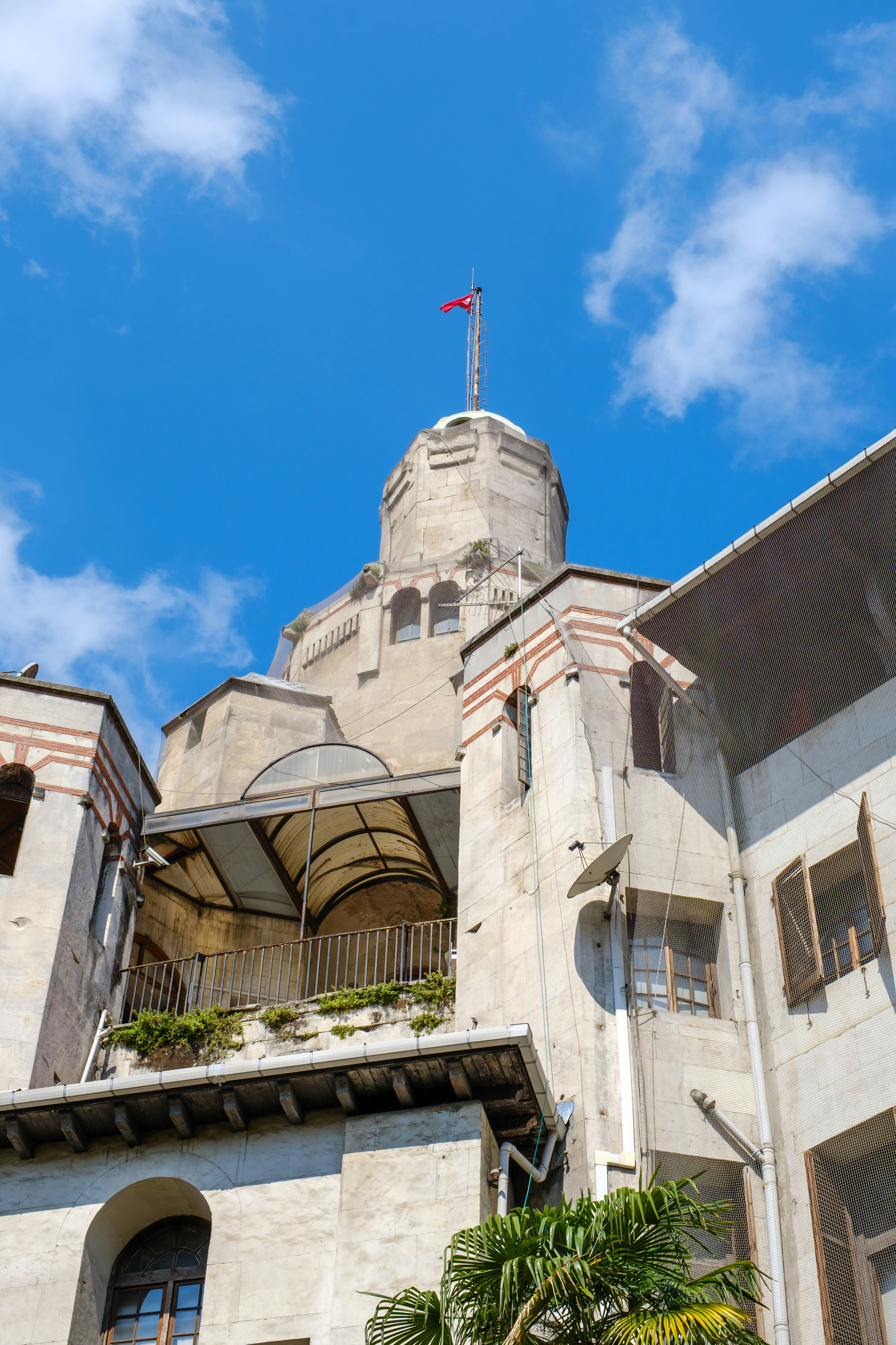 Historic stone building with a flag against a blue sky.