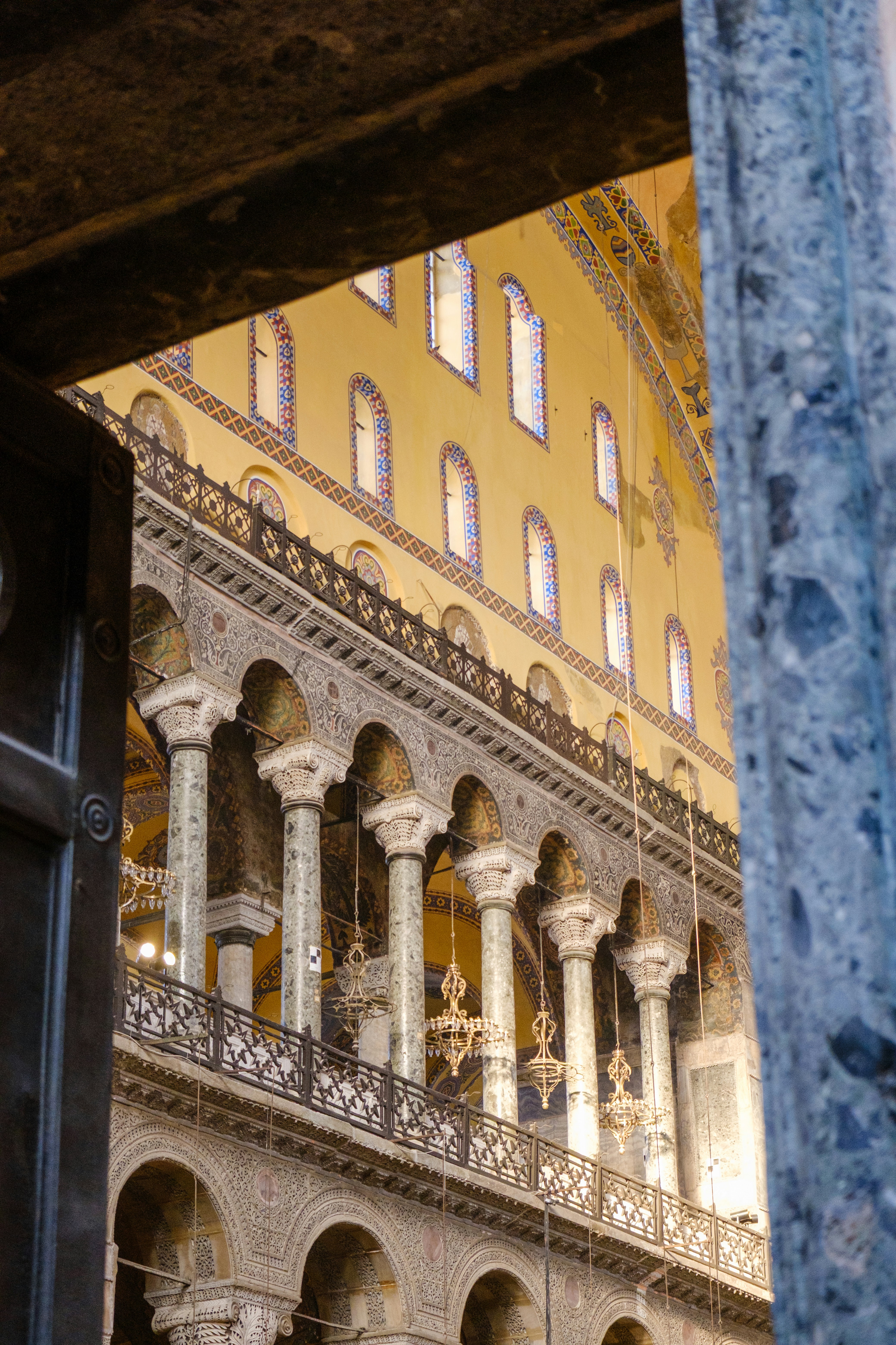 Glimpse into a grand hall with columns, arches, and chandeliers.