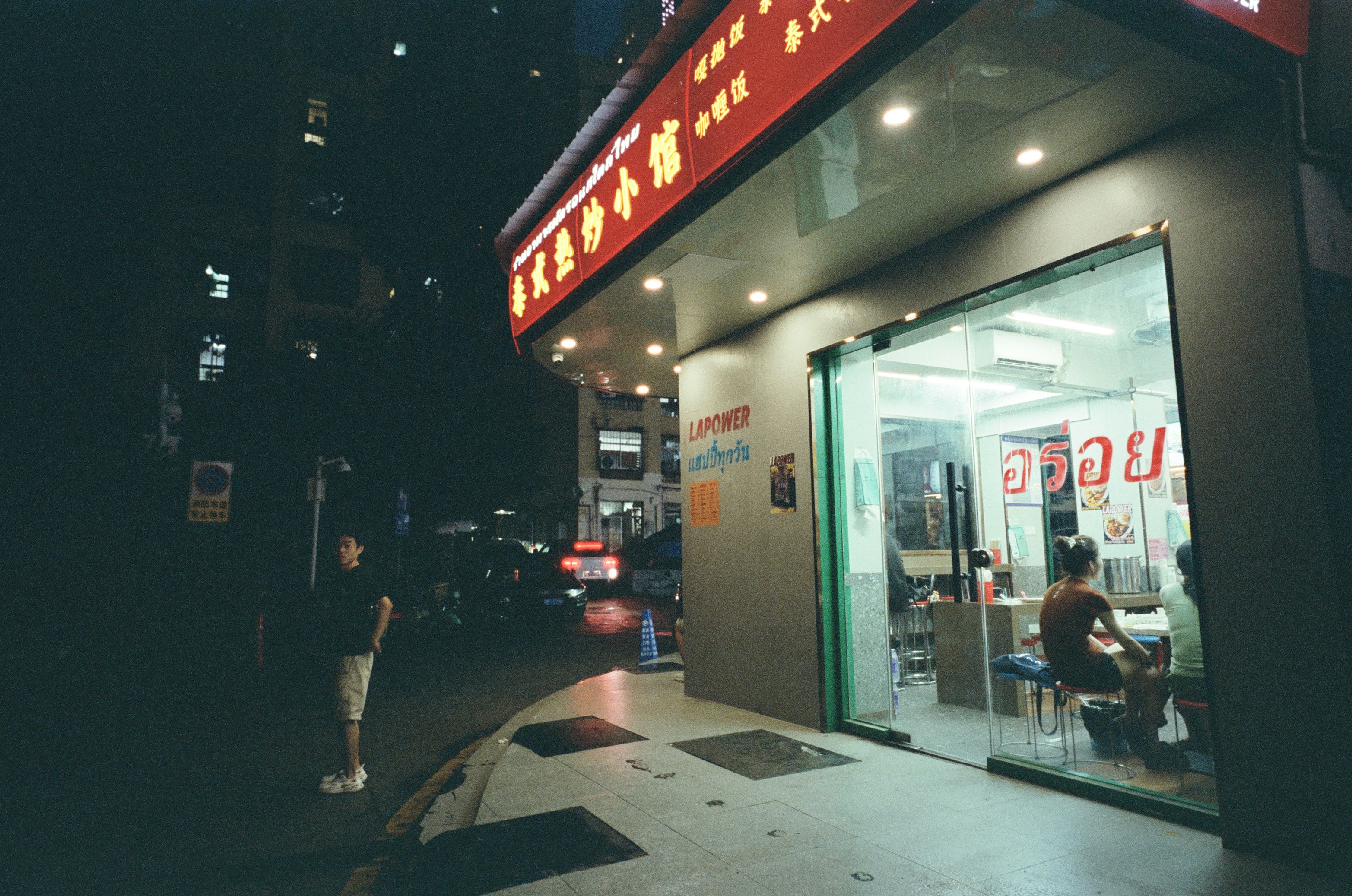 A brightly lit storefront with a red sign at night