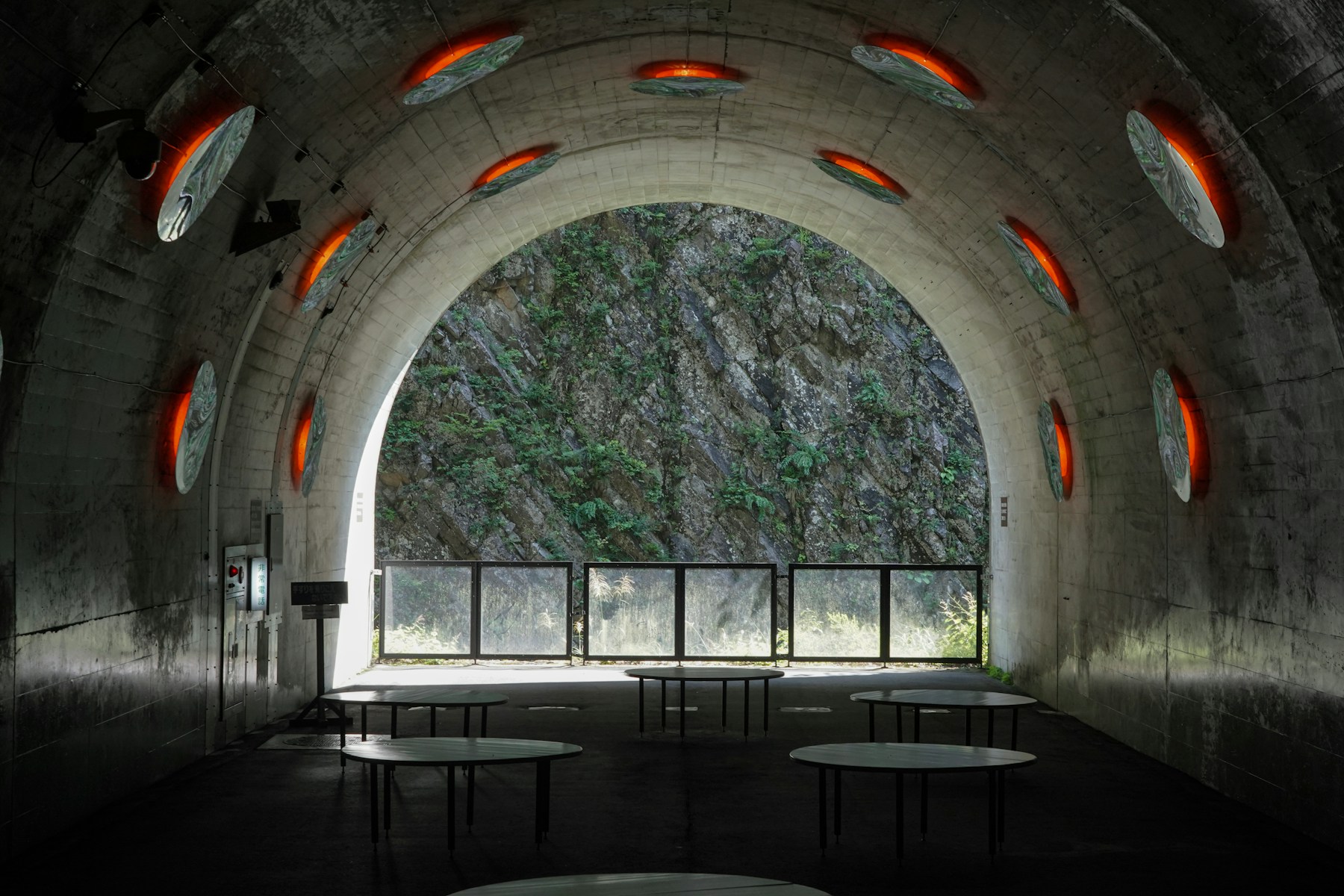 Sala de concreto em arco com luzes acesas e uma montanha ao fundo