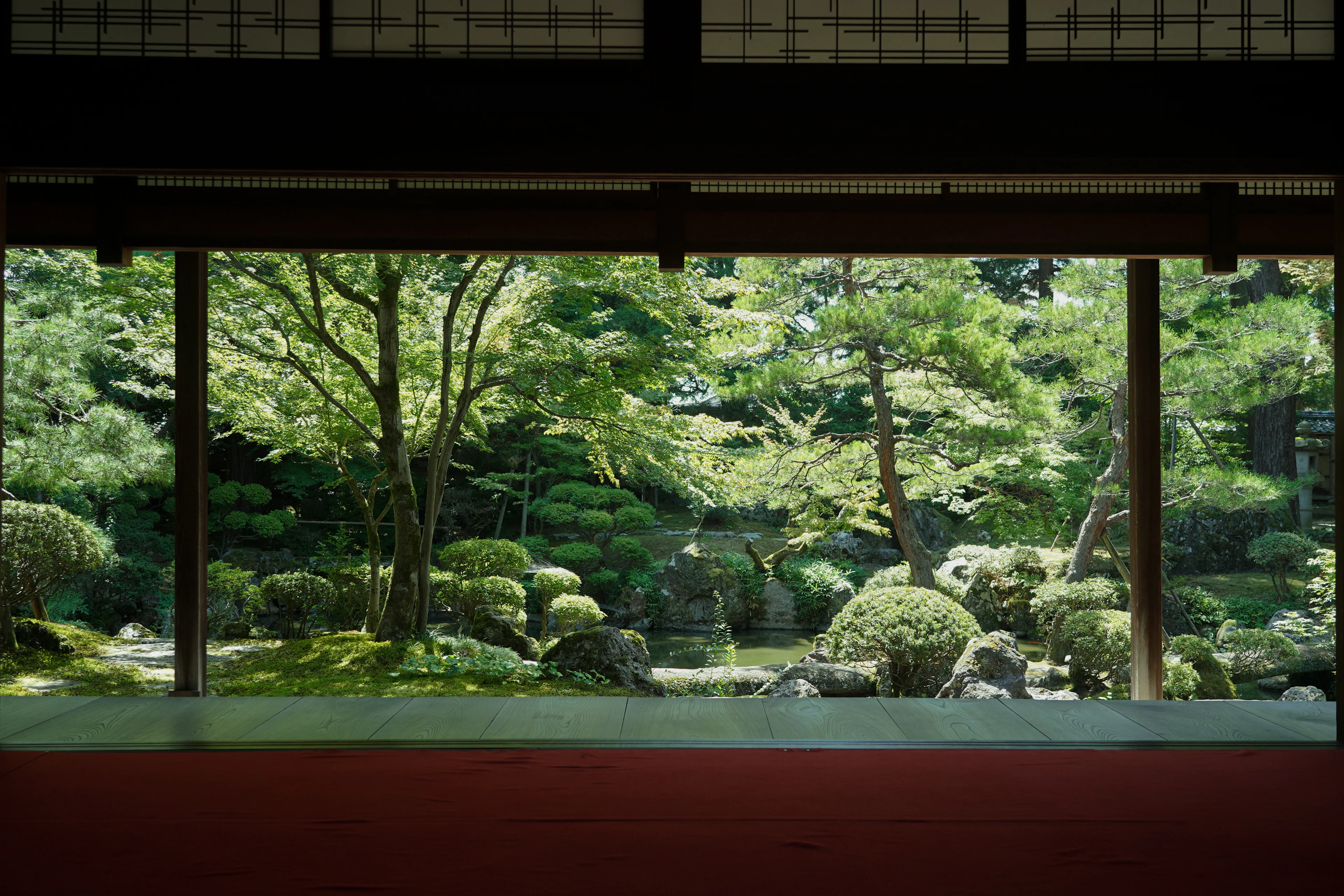 A shaded tatami room opening onto a pond garden with pines and maples, Hoppo Bunka Museum, Niigata, Japan