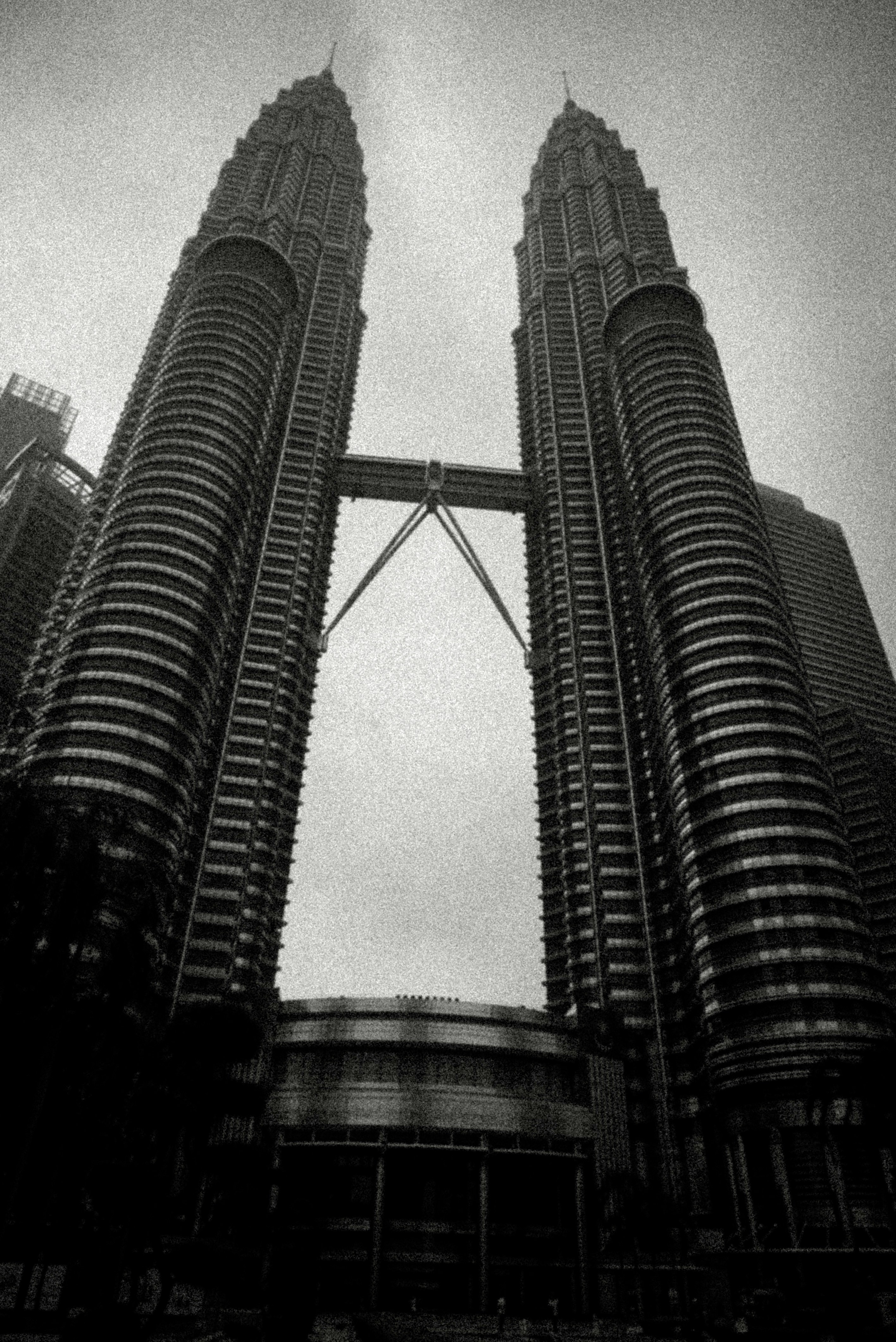 Black and white petronas twin towers against a cloudy sky