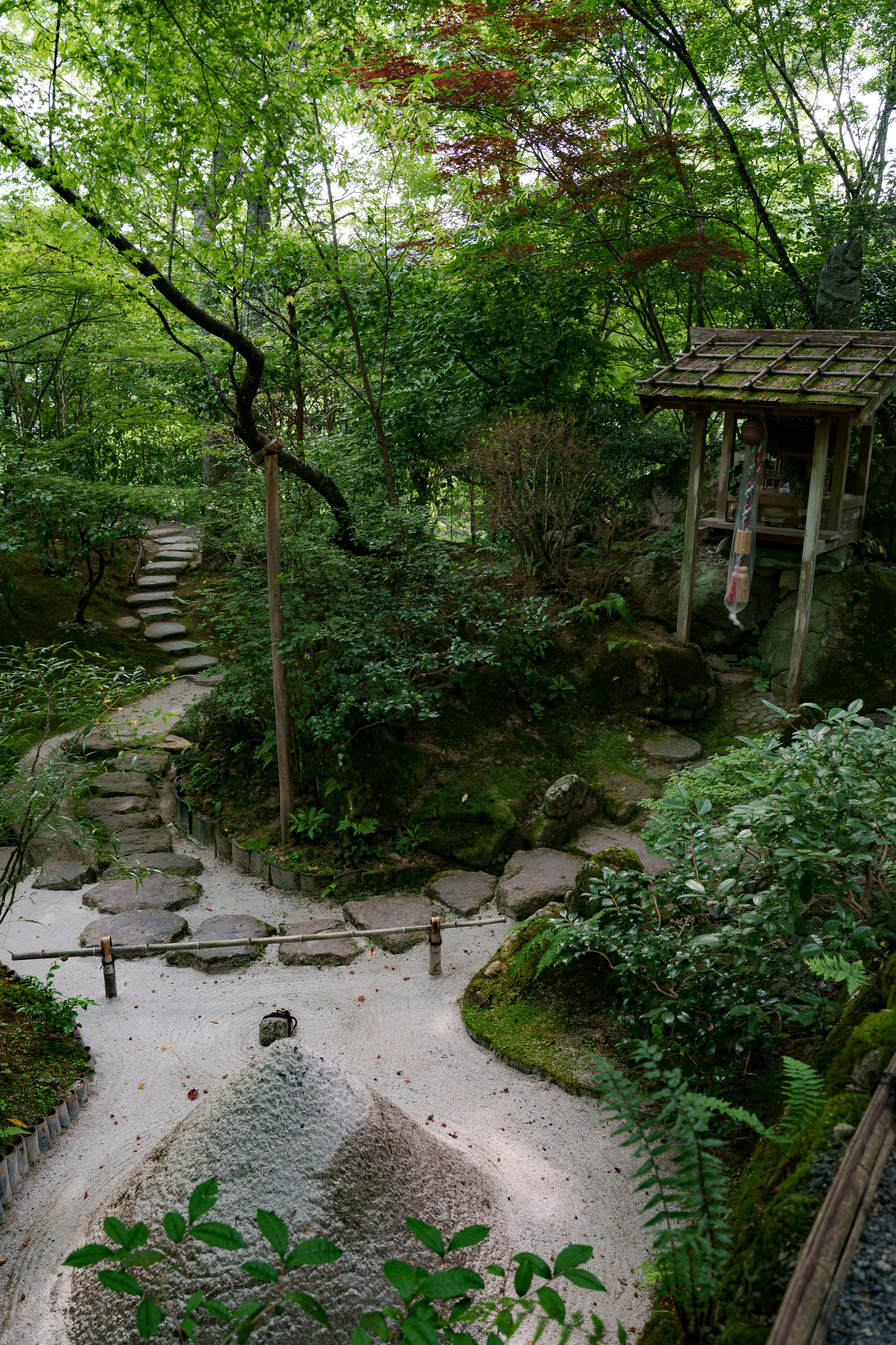 Jardin japonais serein avec un chemin en pierre et une structure en bois.