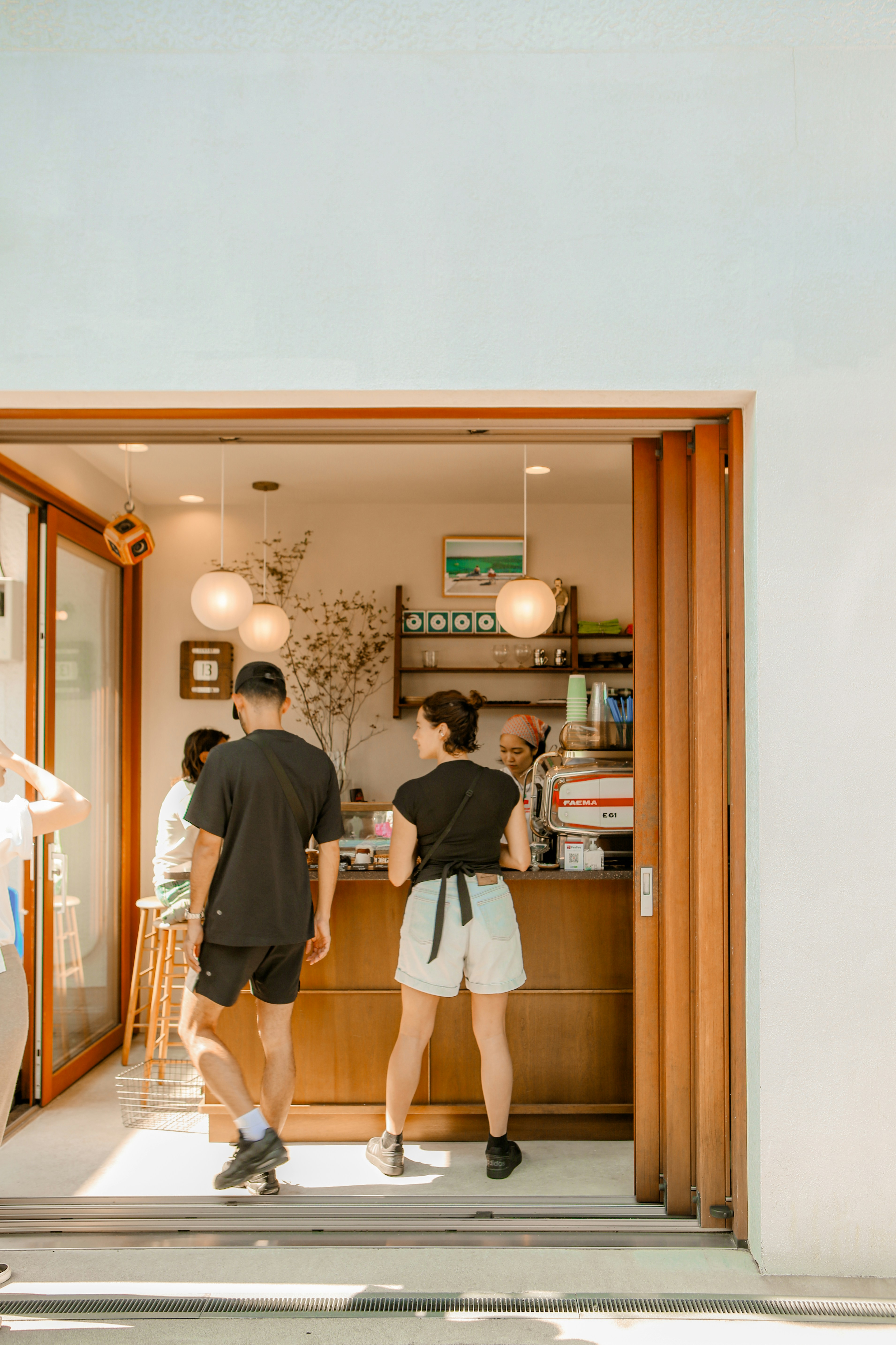 A barista serves customers in a bright, modern cafe.