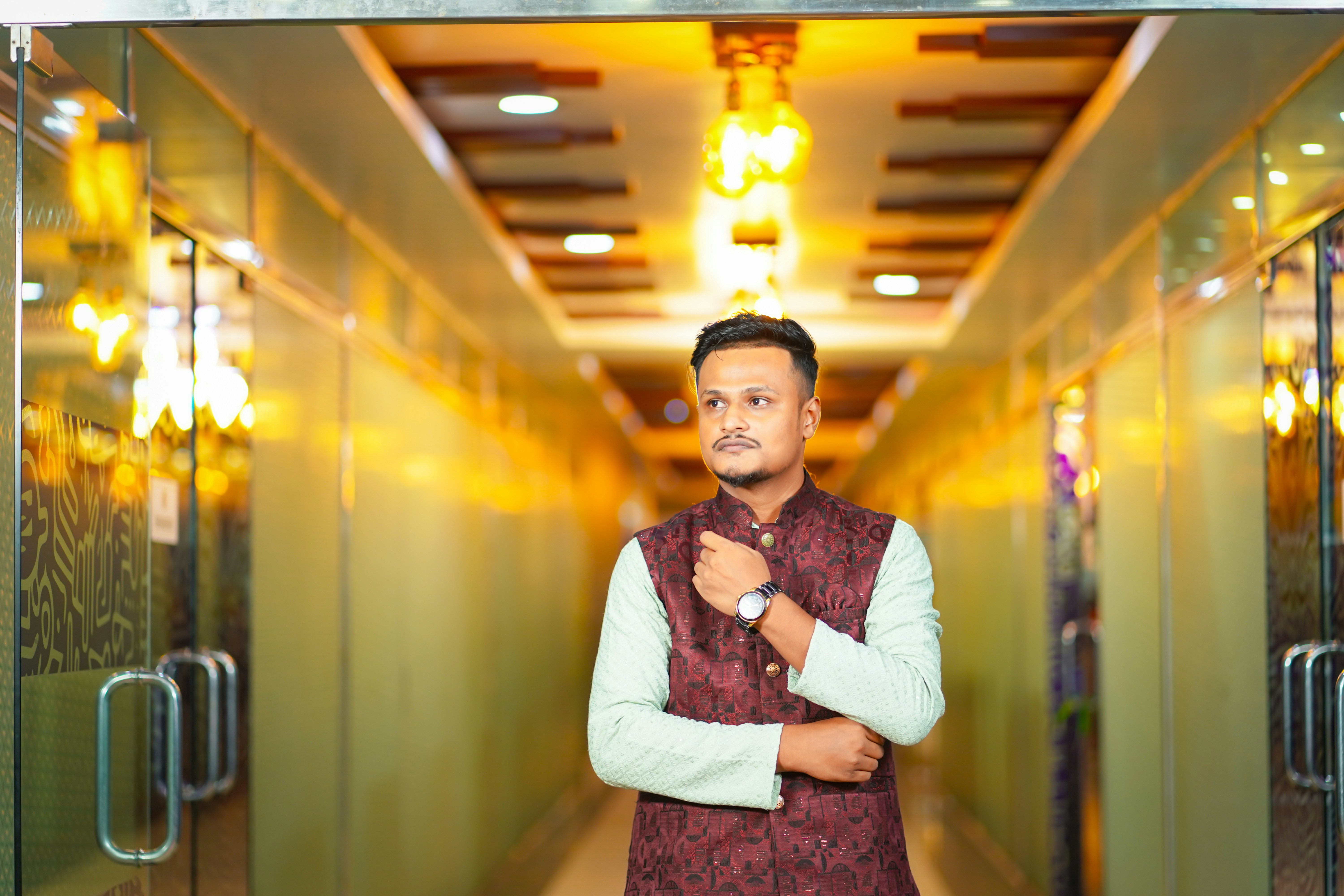 A man in traditional attire stands in a well-lit hallway
