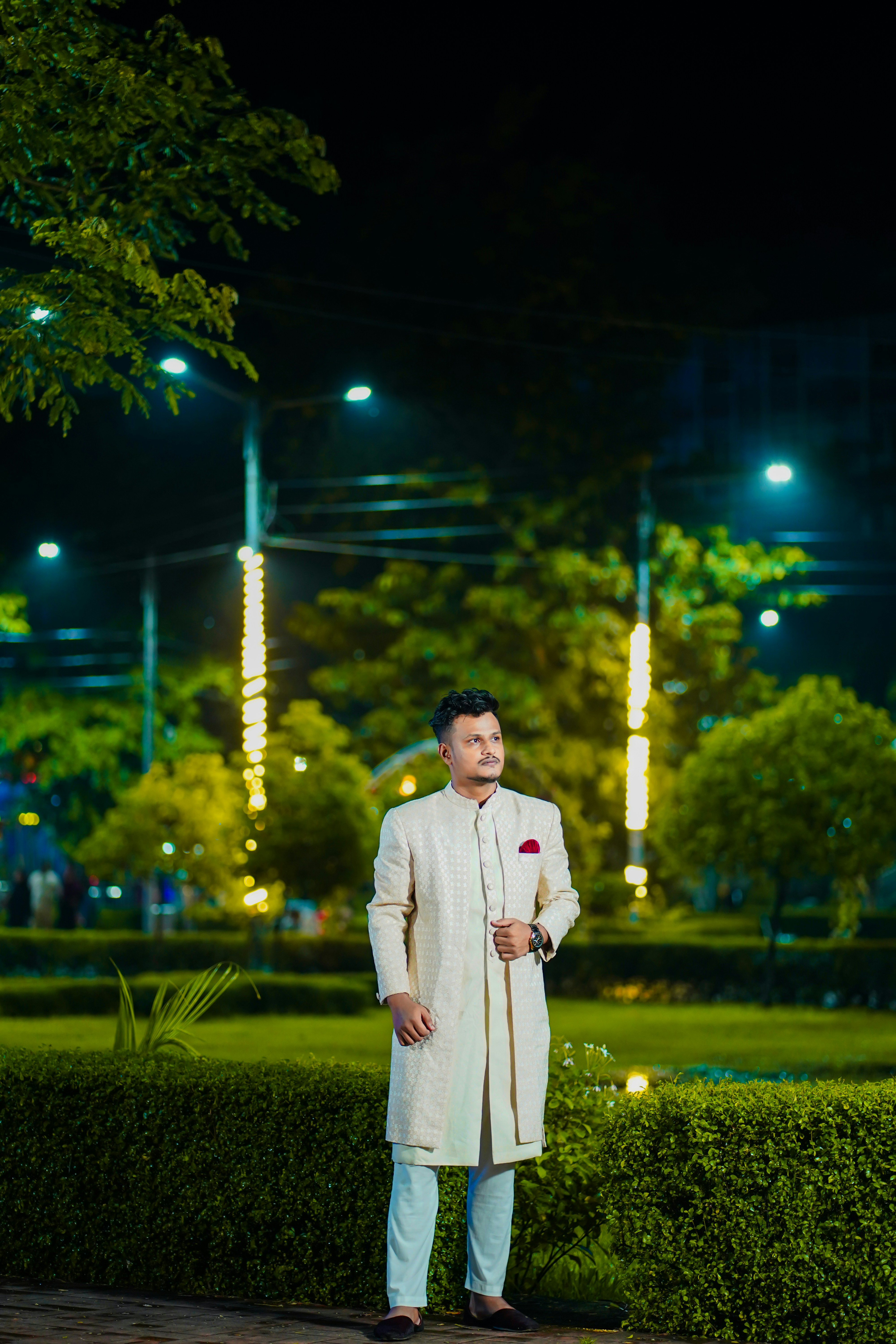 Pria dengan pakaian tradisional berdiri di luar ruangan pada malam hari.
