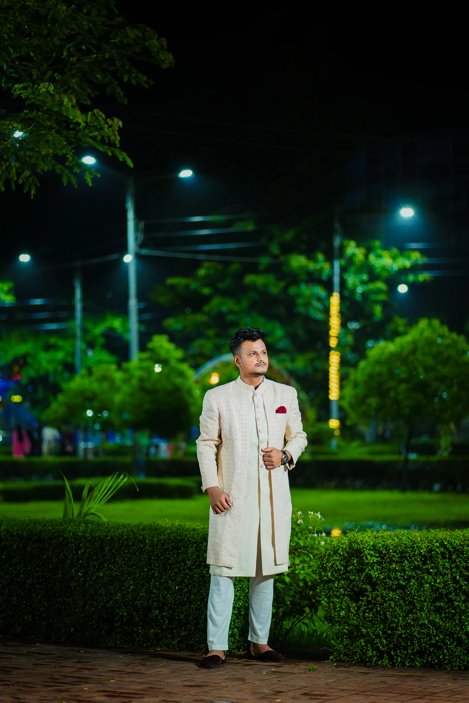Man in a cream sherwani outdoors at night