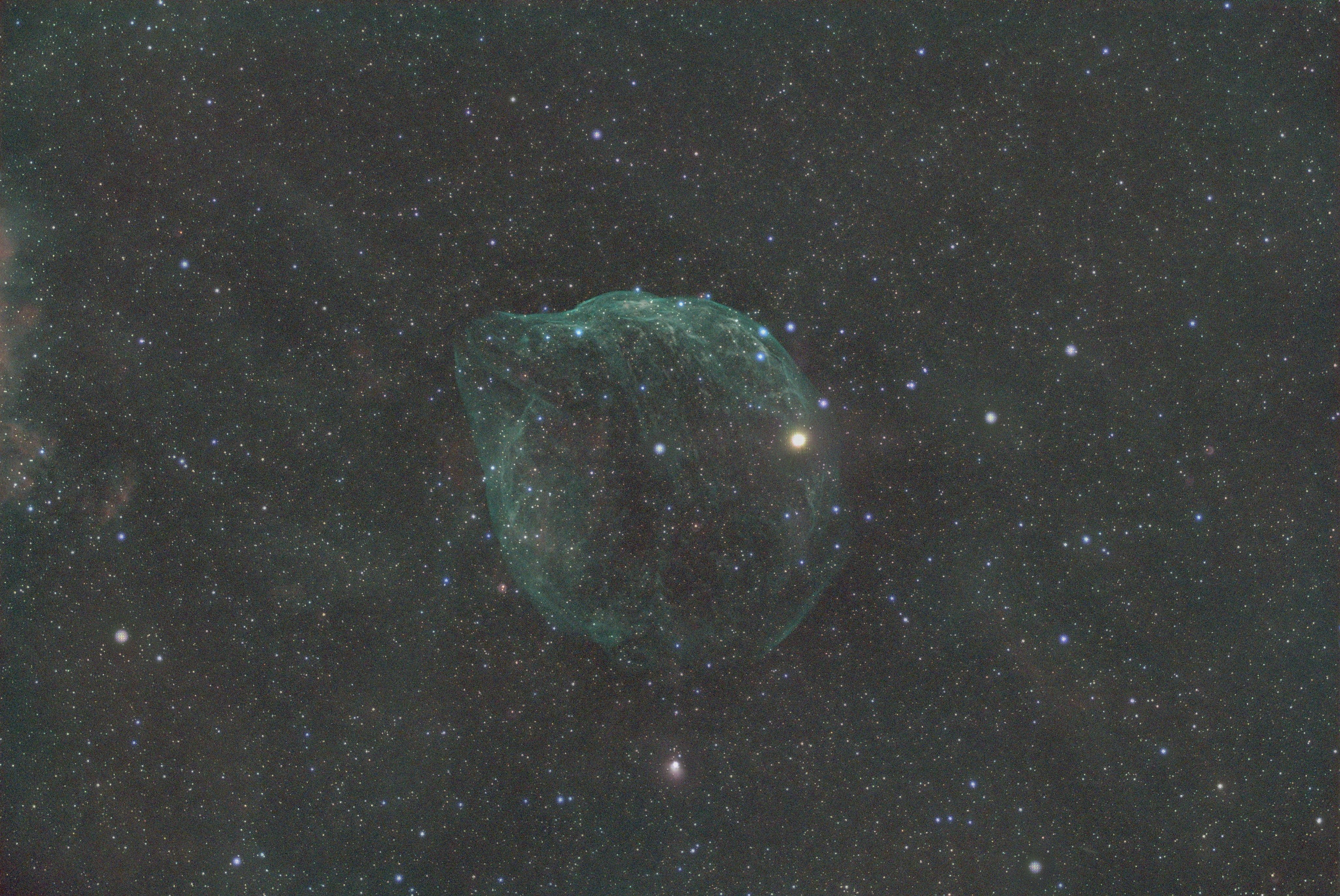 A faint, bubble-like nebula in a star-filled cosmic sky.