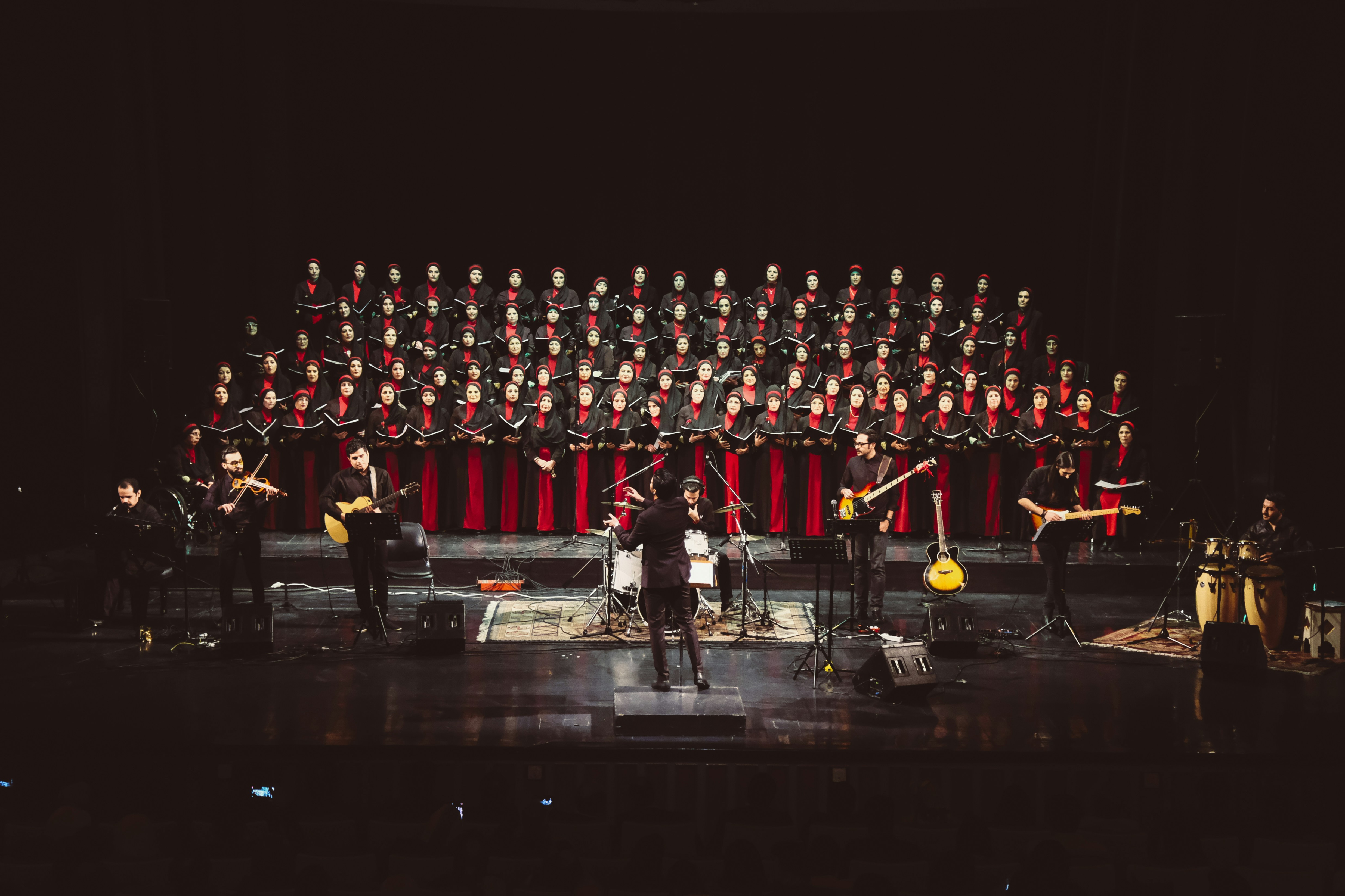 A large choir and band perform on a dark stage.