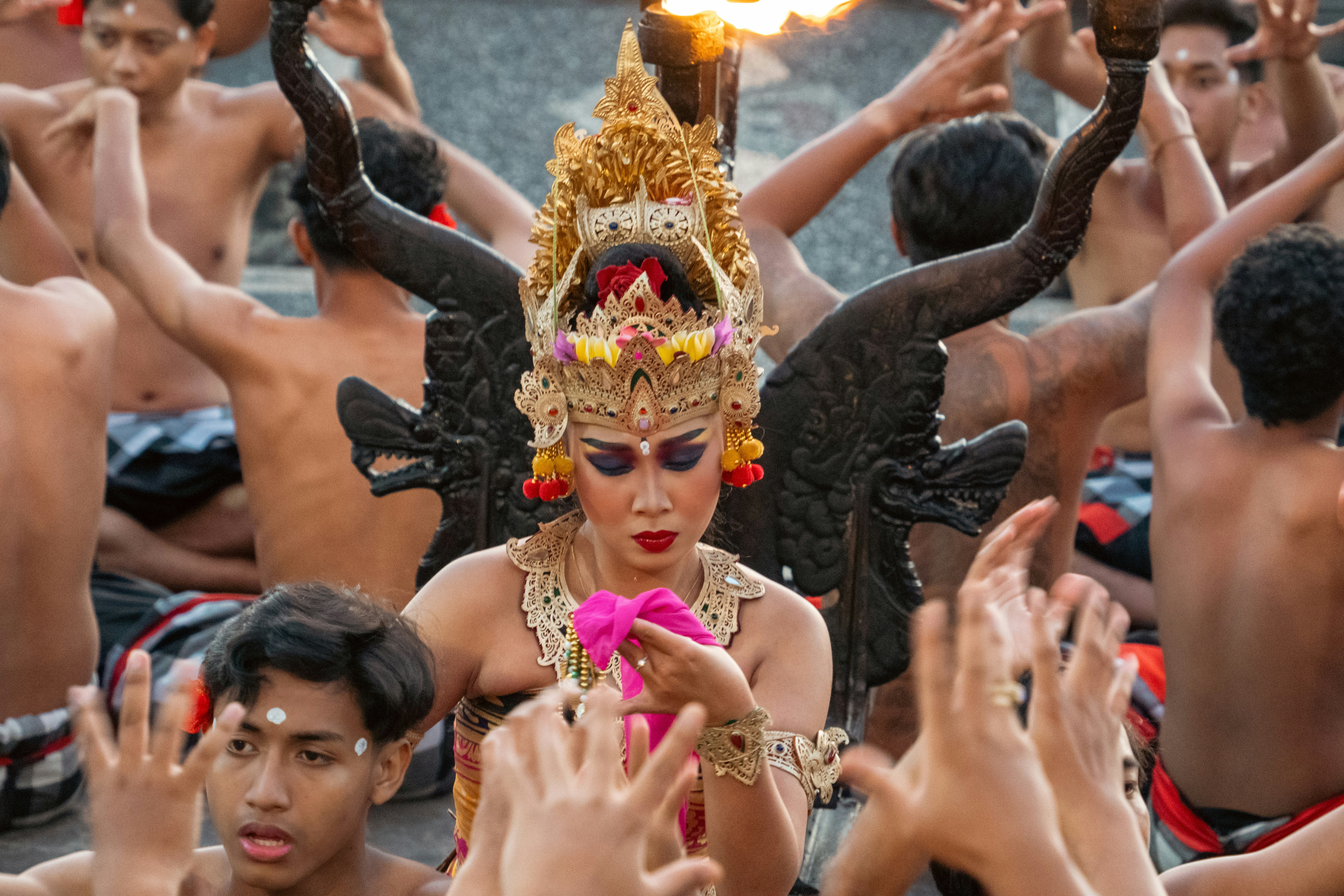 Elaborate dancer performs surrounded by men in traditional ritual