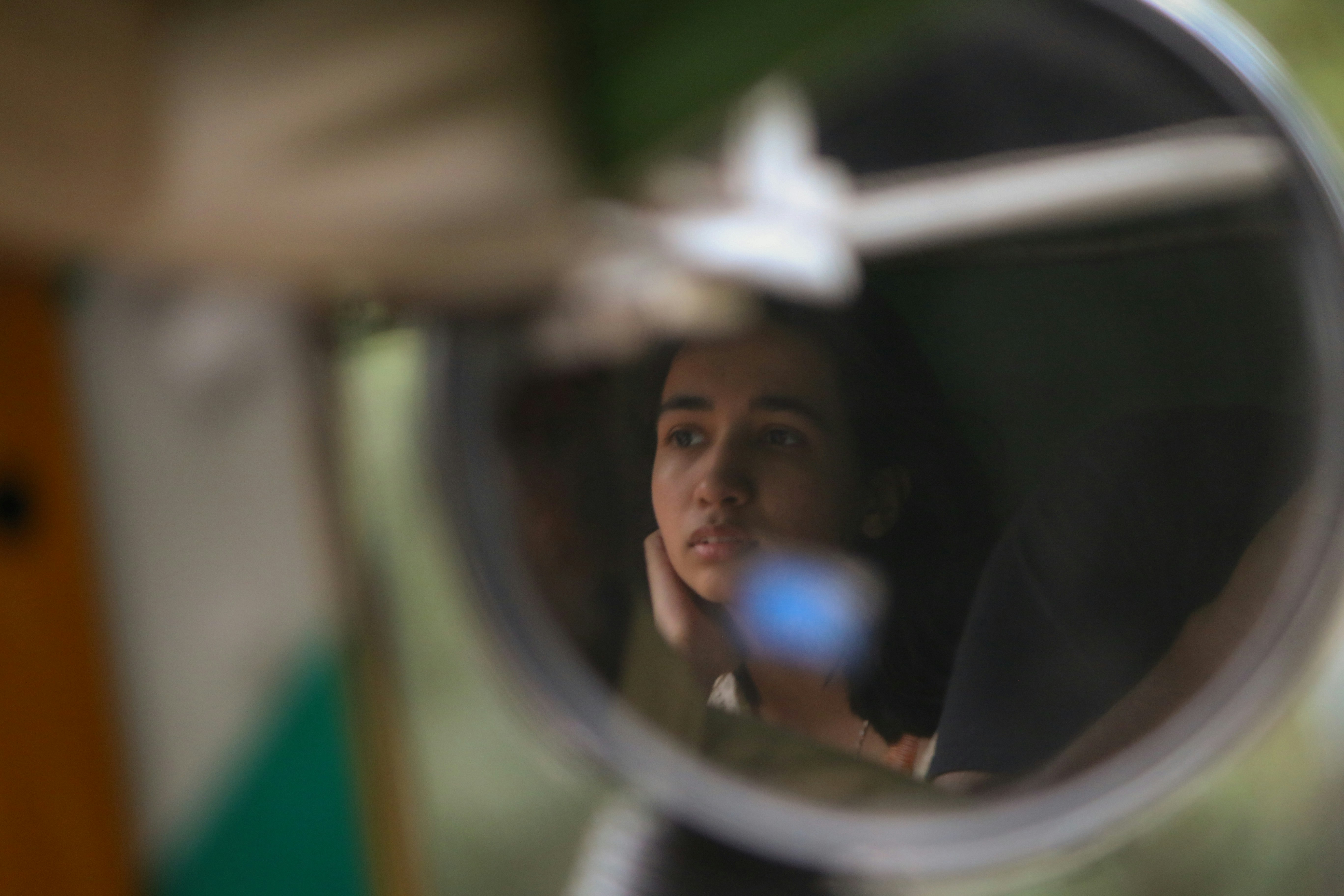El rostro pensativo de una mujer reflejado en un espejo circular