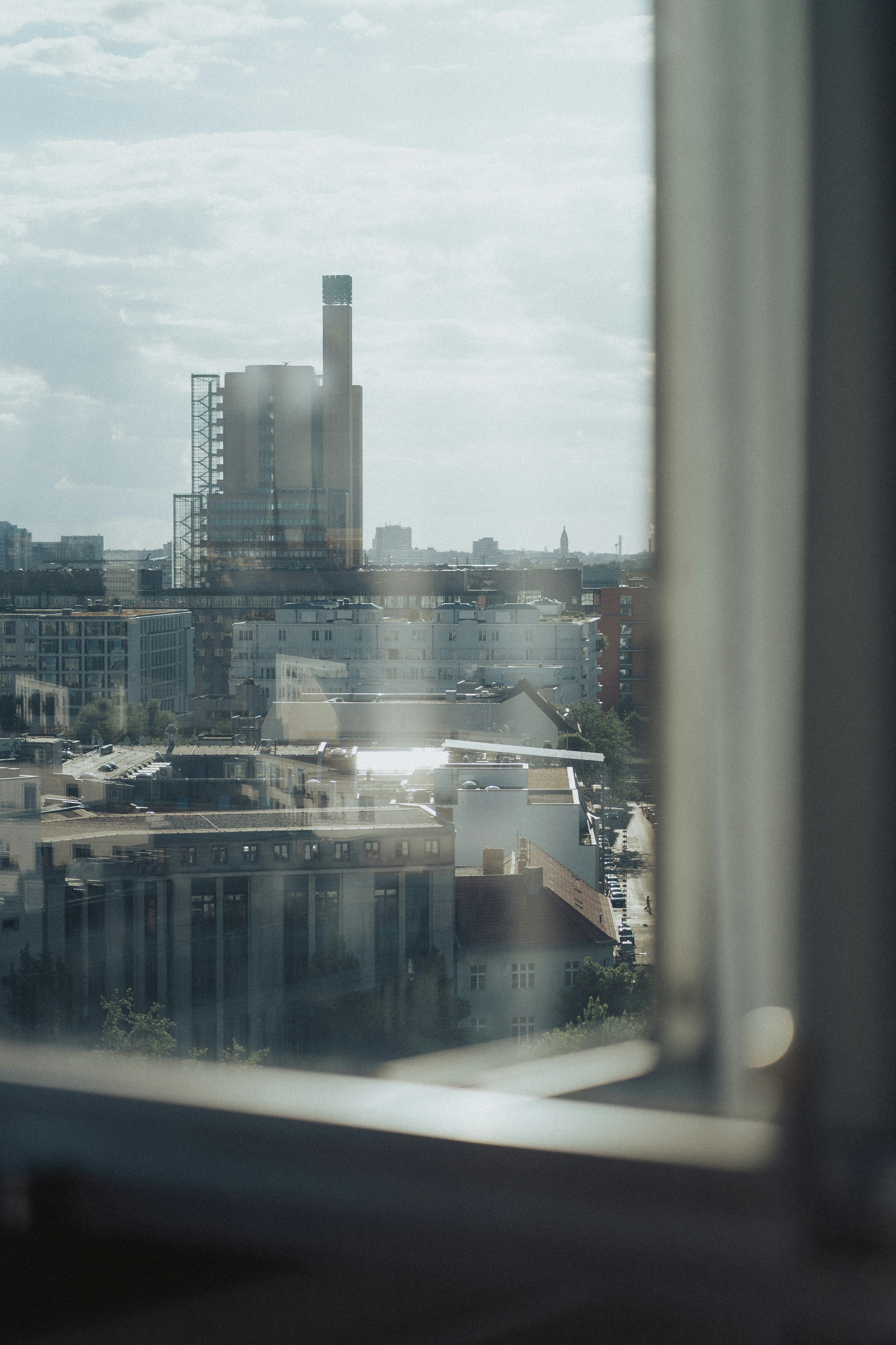 Stadtansicht durch ein Fenster mit Sonnenlicht, das auf Gebäude reflektiert.