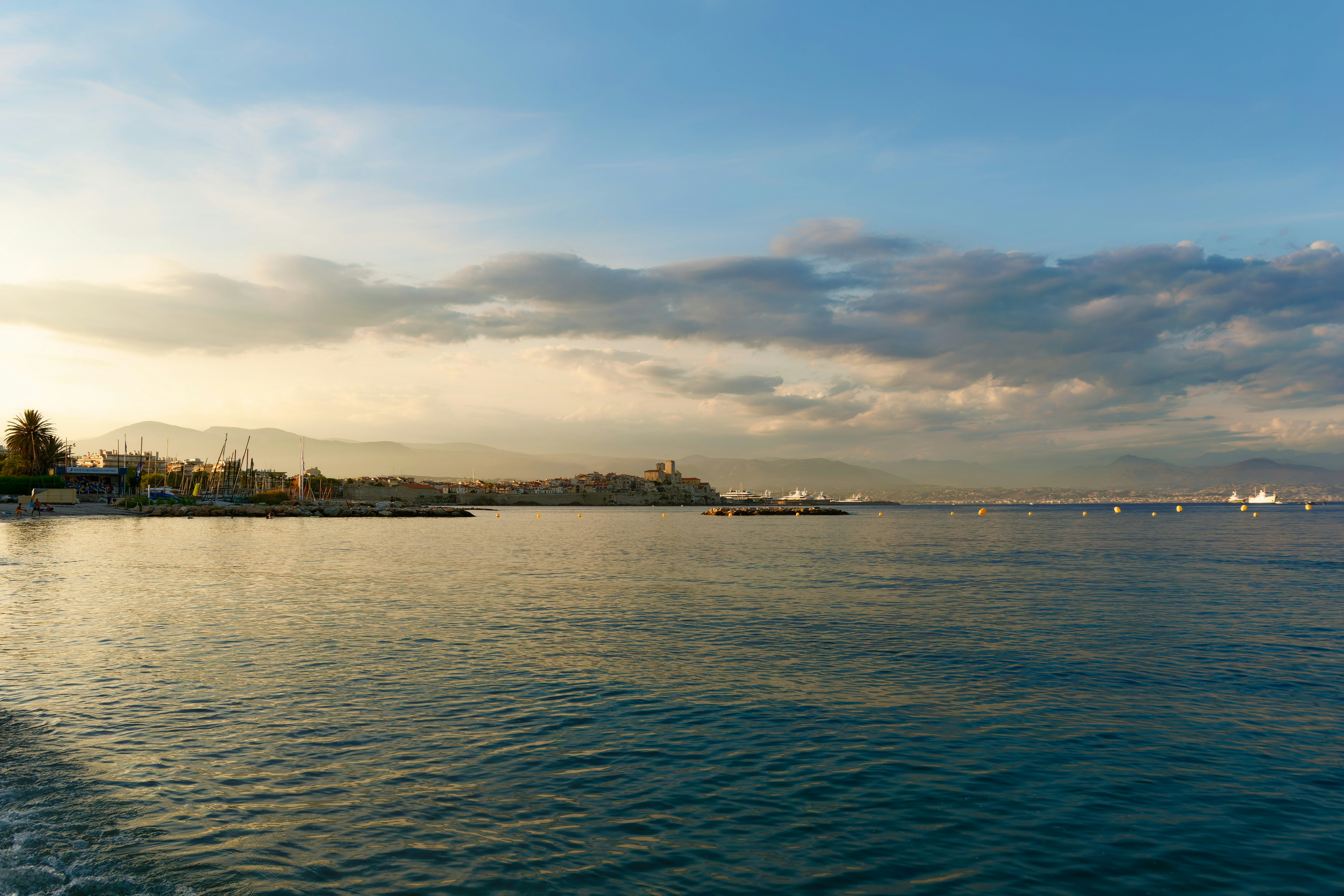 Küstenstadt mit Bergen und einem Pier bei Sonnenuntergang