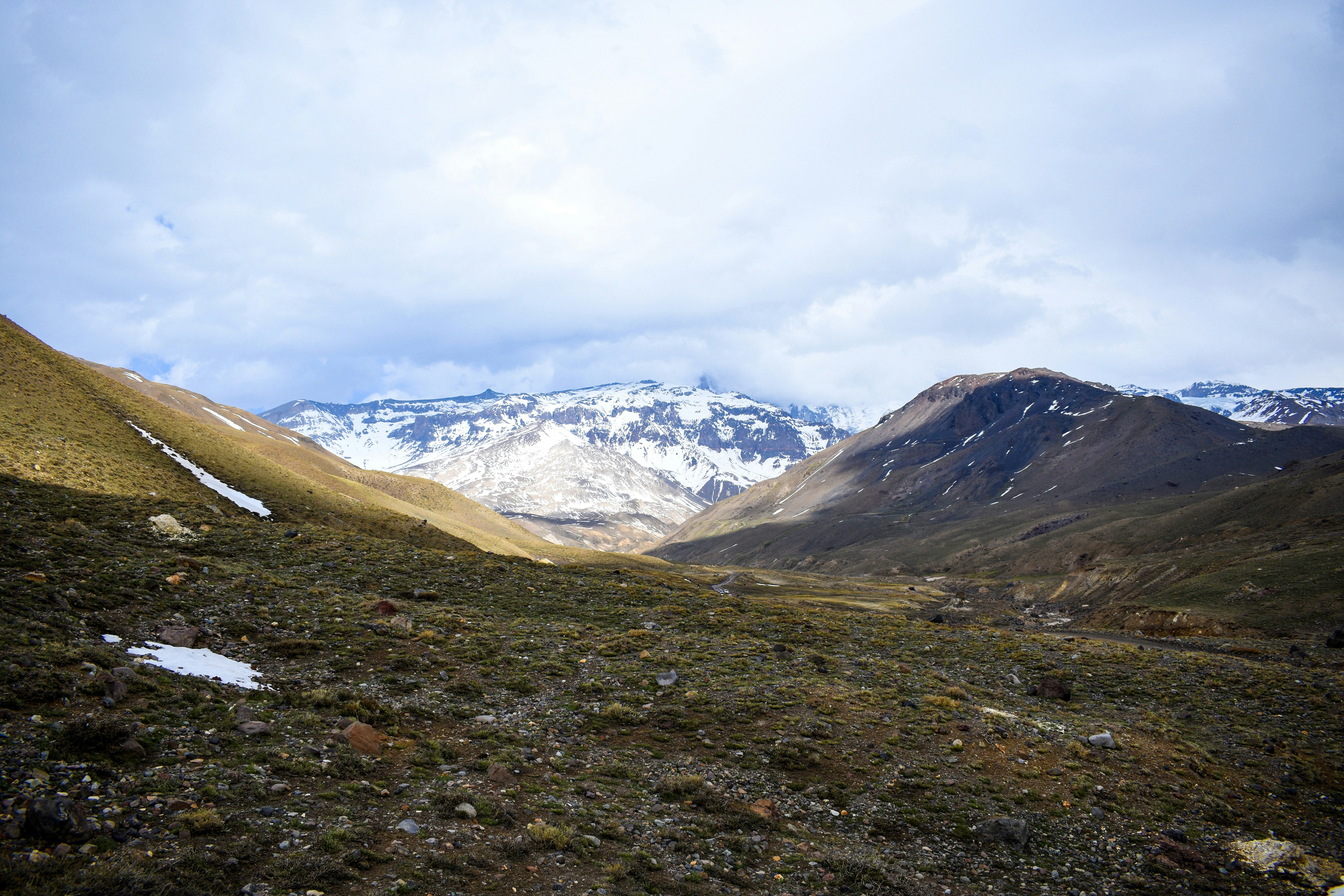Snow-covered mountains rise above a rugged valley landscape.