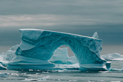 A massive arch-shaped iceberg floats in the cold ocean
