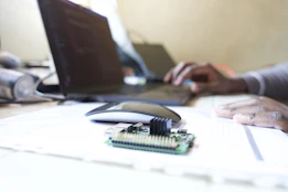 Small circuit board on a desk with person typing.