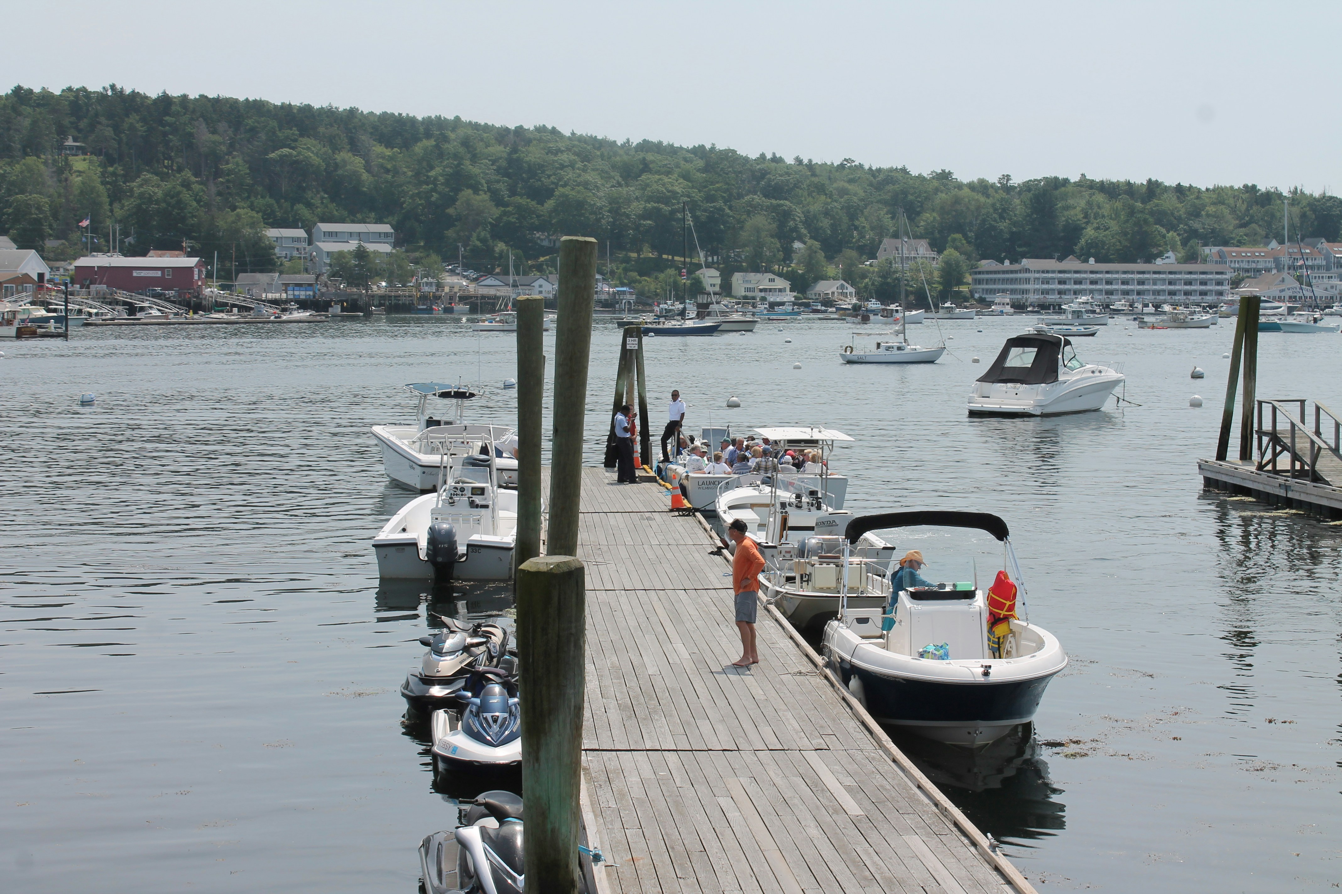 Person on wooden dock with boats in a harbor