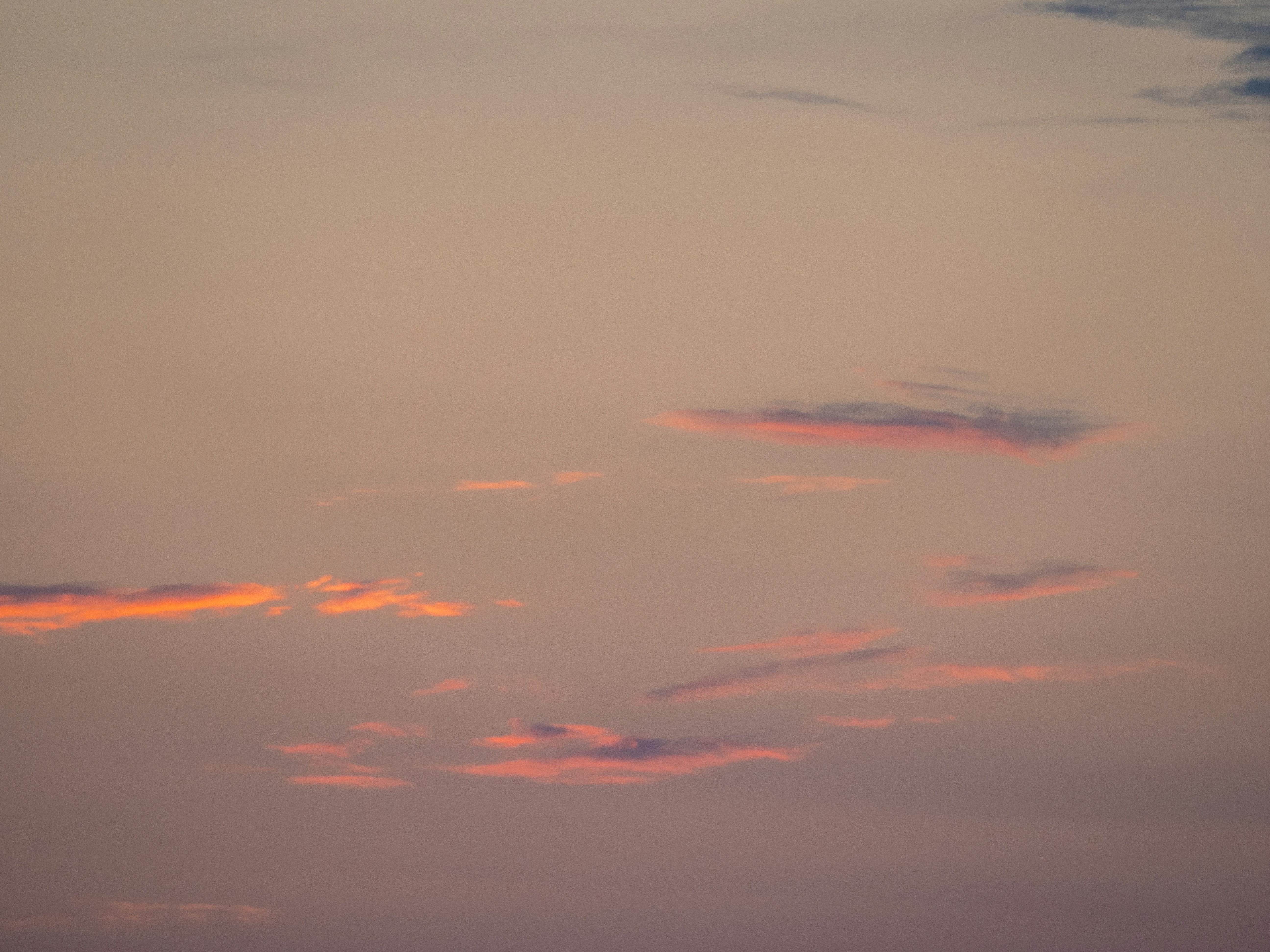 Ein Himmel mit sanften rosa und orangefarbenen Wolken bei Sonnenuntergang.