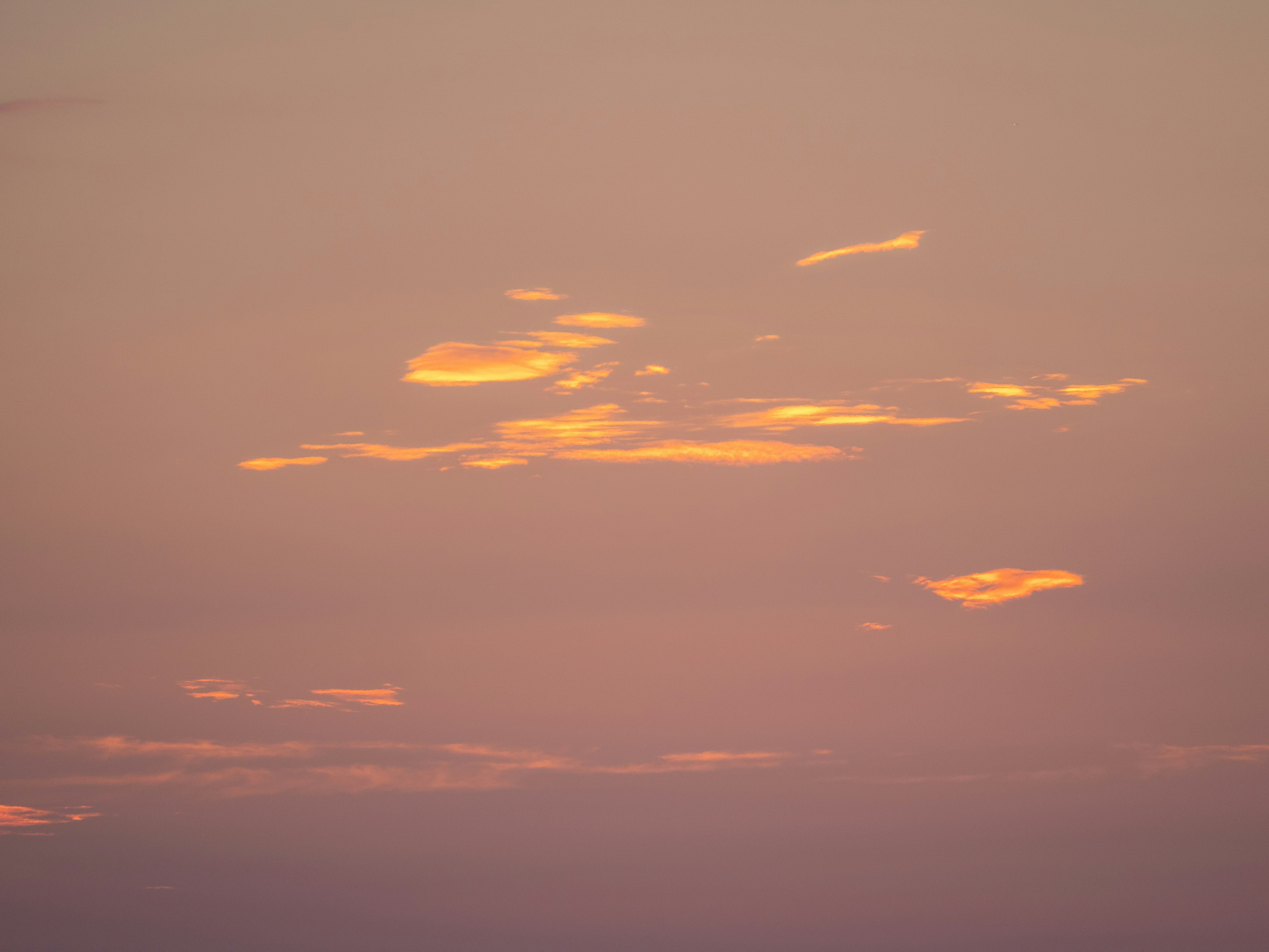 Warmer Himmel mit verstreuten Wolken bei Sonnenuntergang.
