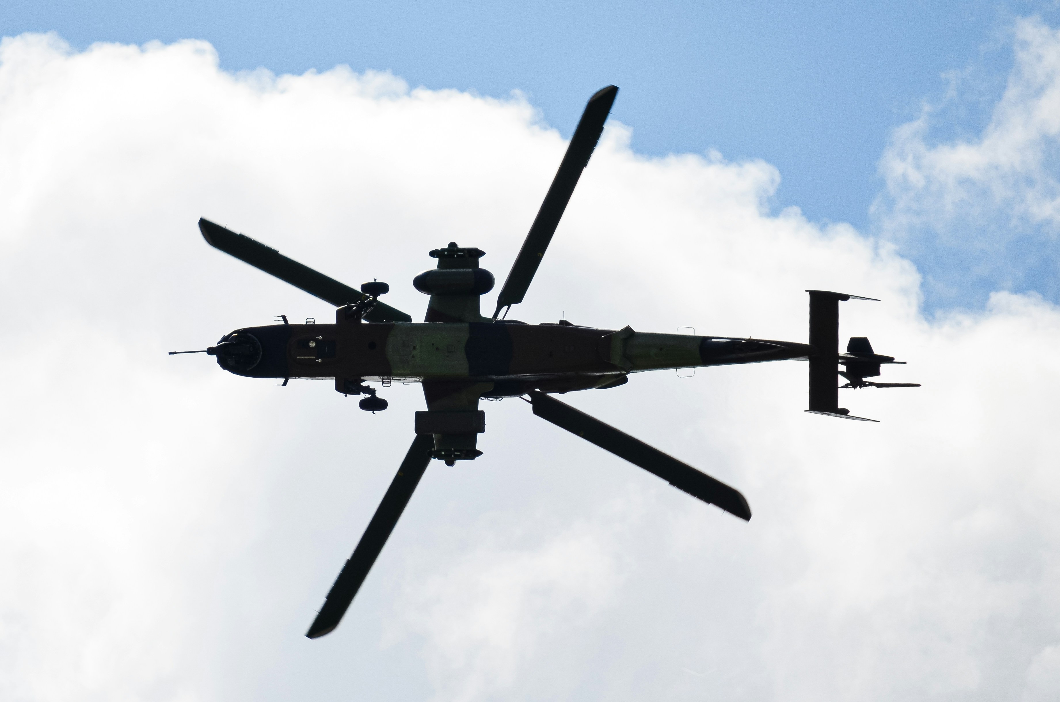 Helicóptero de ataque em silhueta voando sob um céu nublado