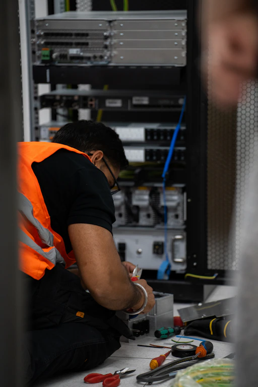 Technician working on server equipment with tools.