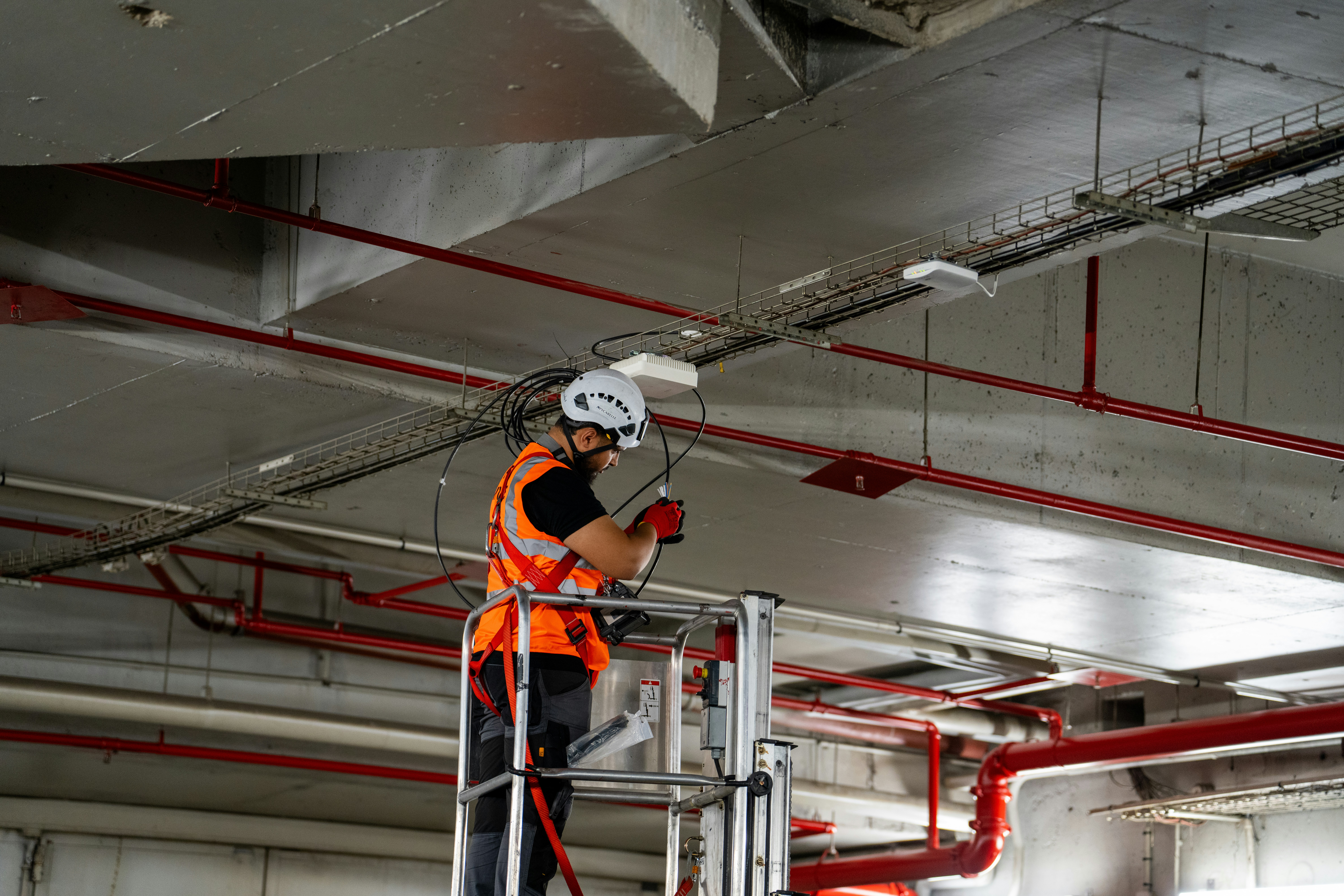 Construction worker on lift installing ceiling components.