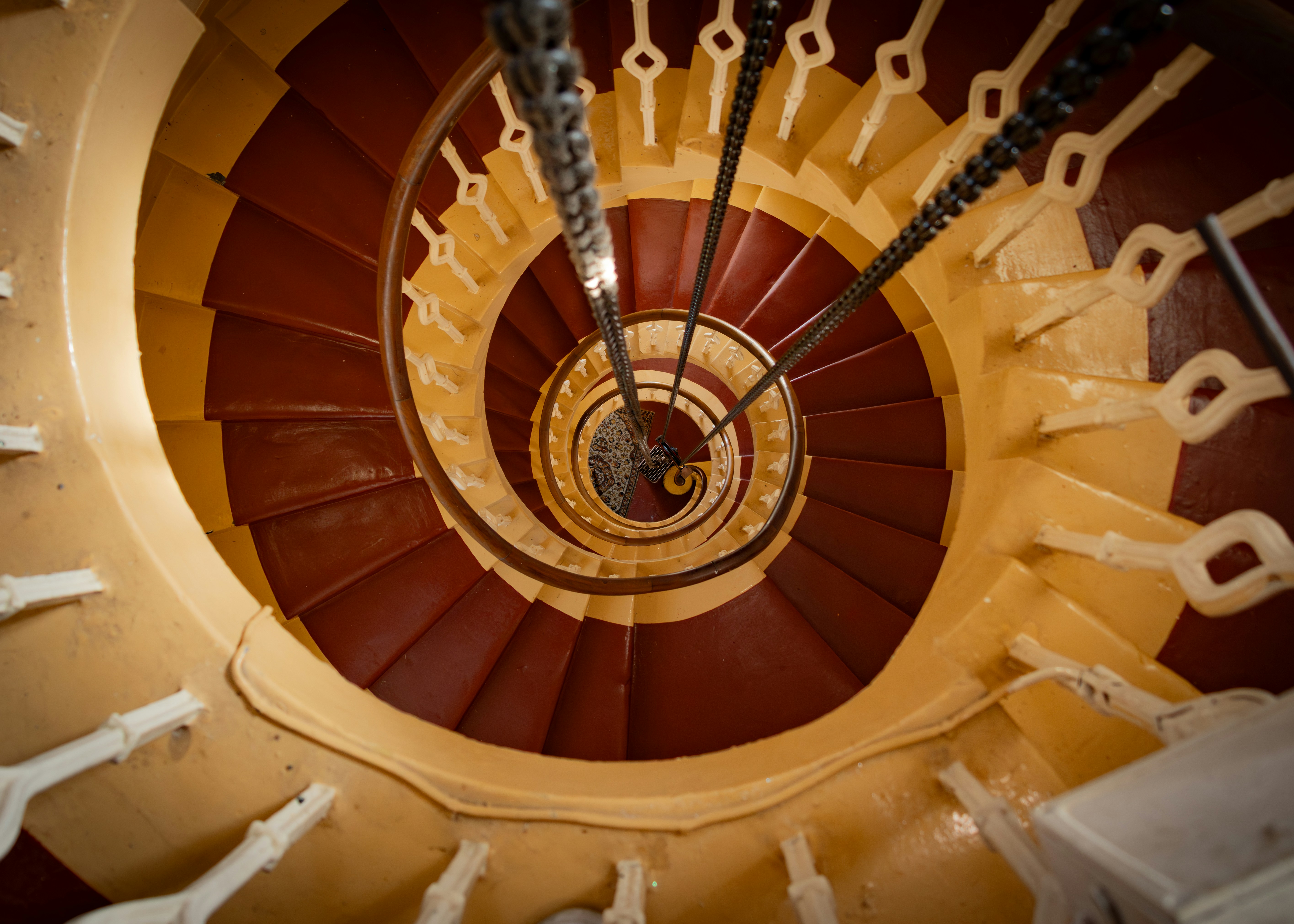 Looking down a spiral staircase with red steps.
