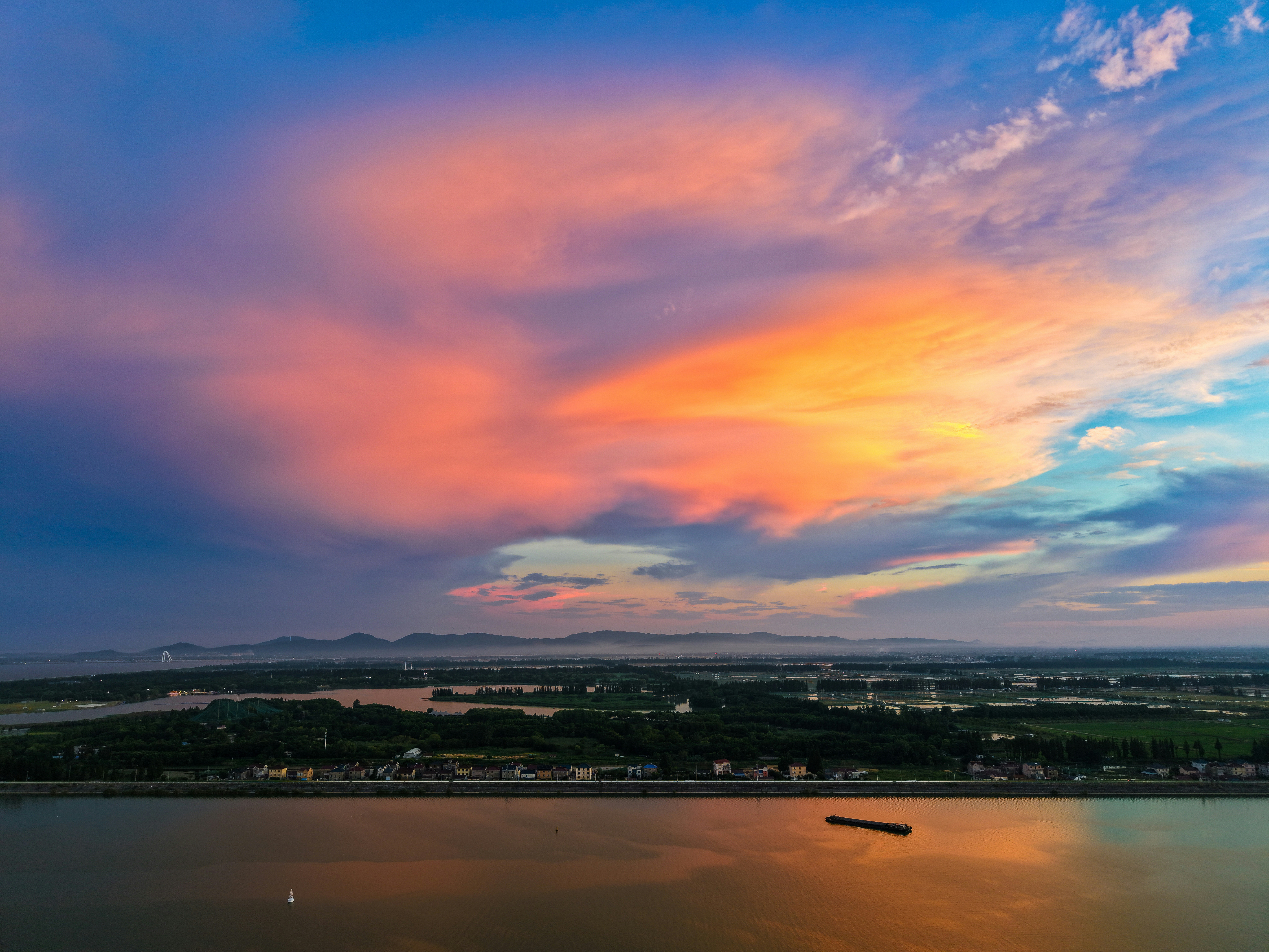 Vibrant sunset sky over a calm river and distant land