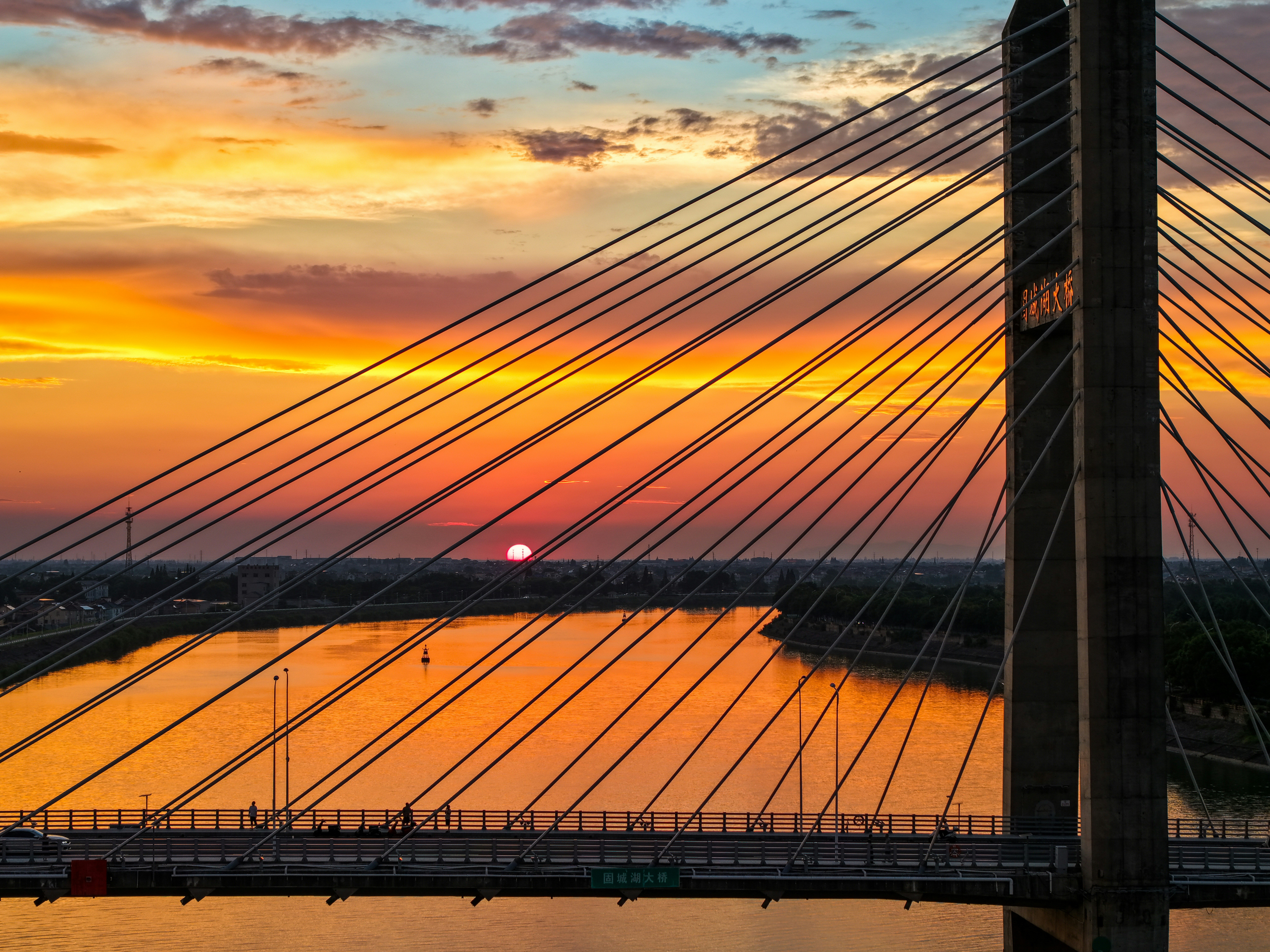 Vibrant sunset illuminates a cable-stayed bridge over water