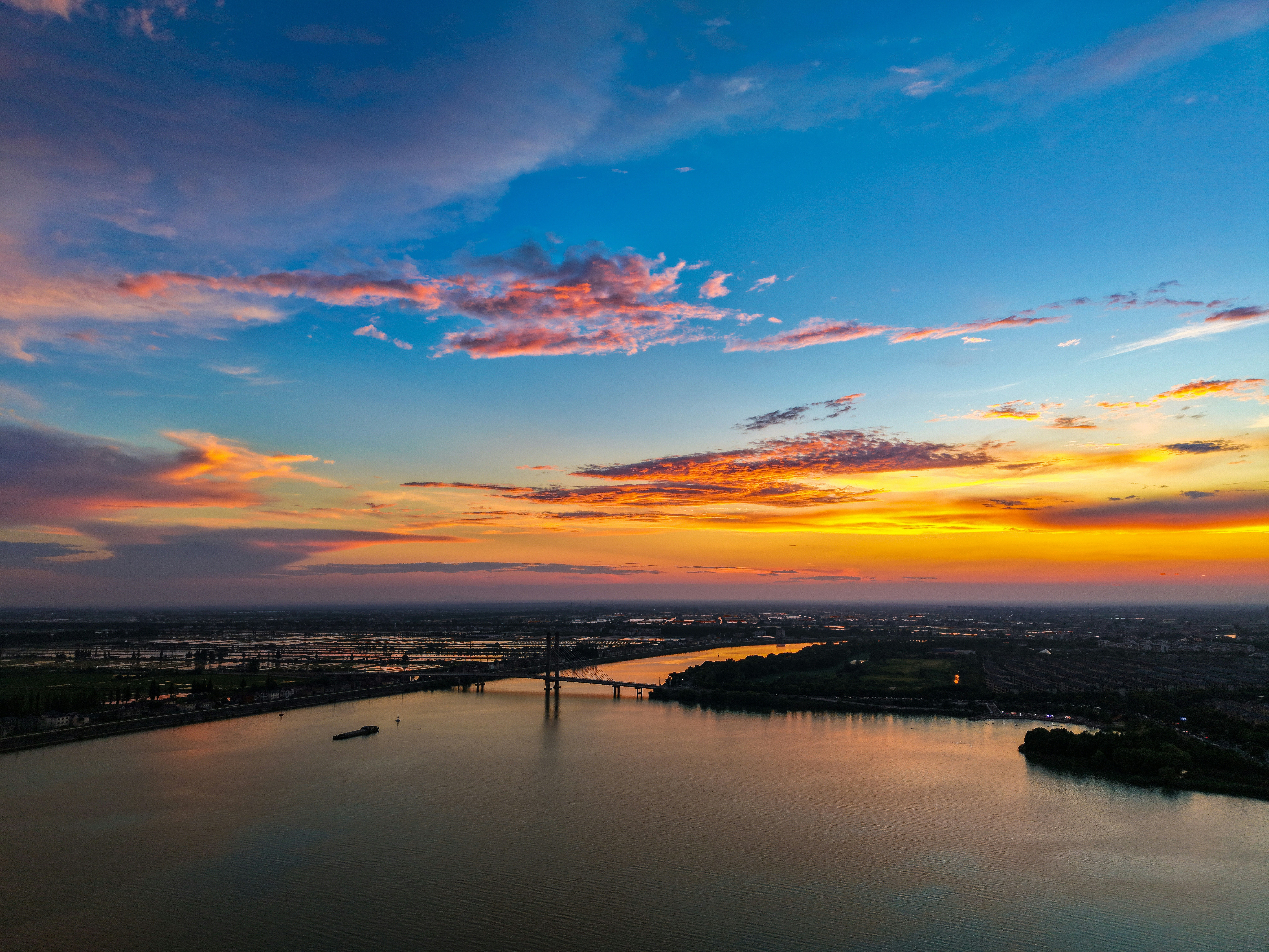 Vibrant sunset sky above a river and bridge