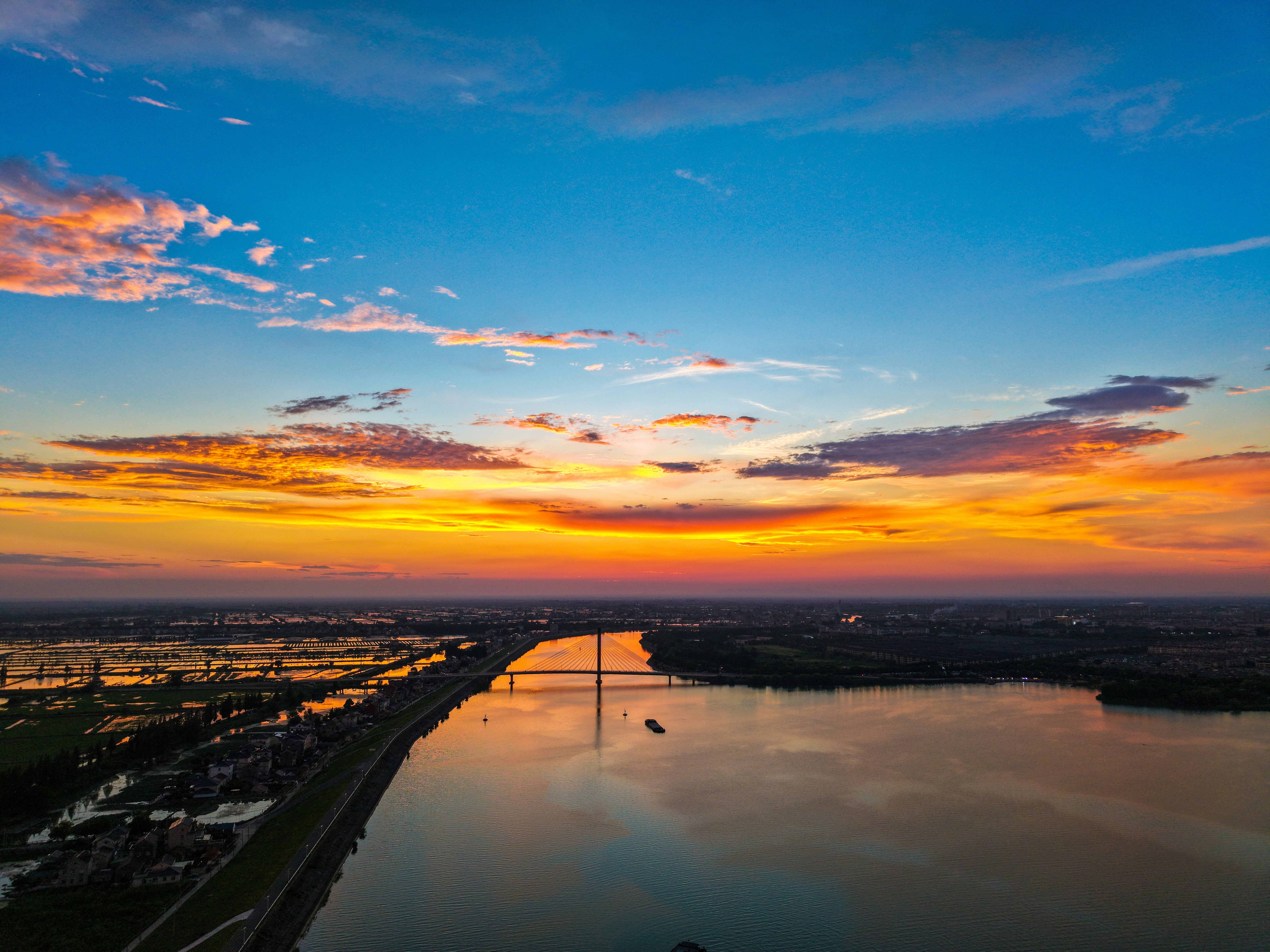 Vibrant sunset sky over a long river and distant city