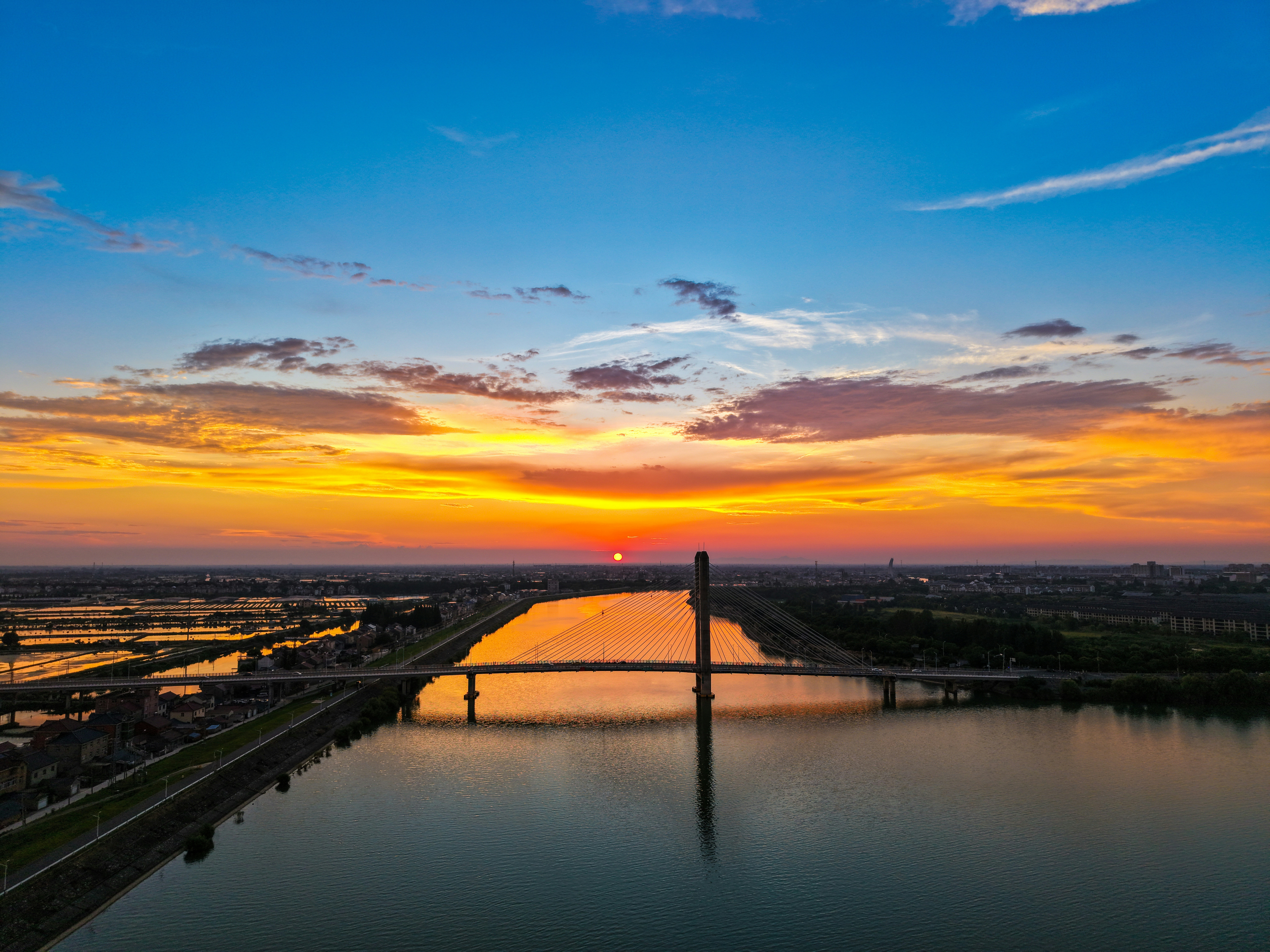 Vibrant sunset sky above a bridge crossing a calm river
