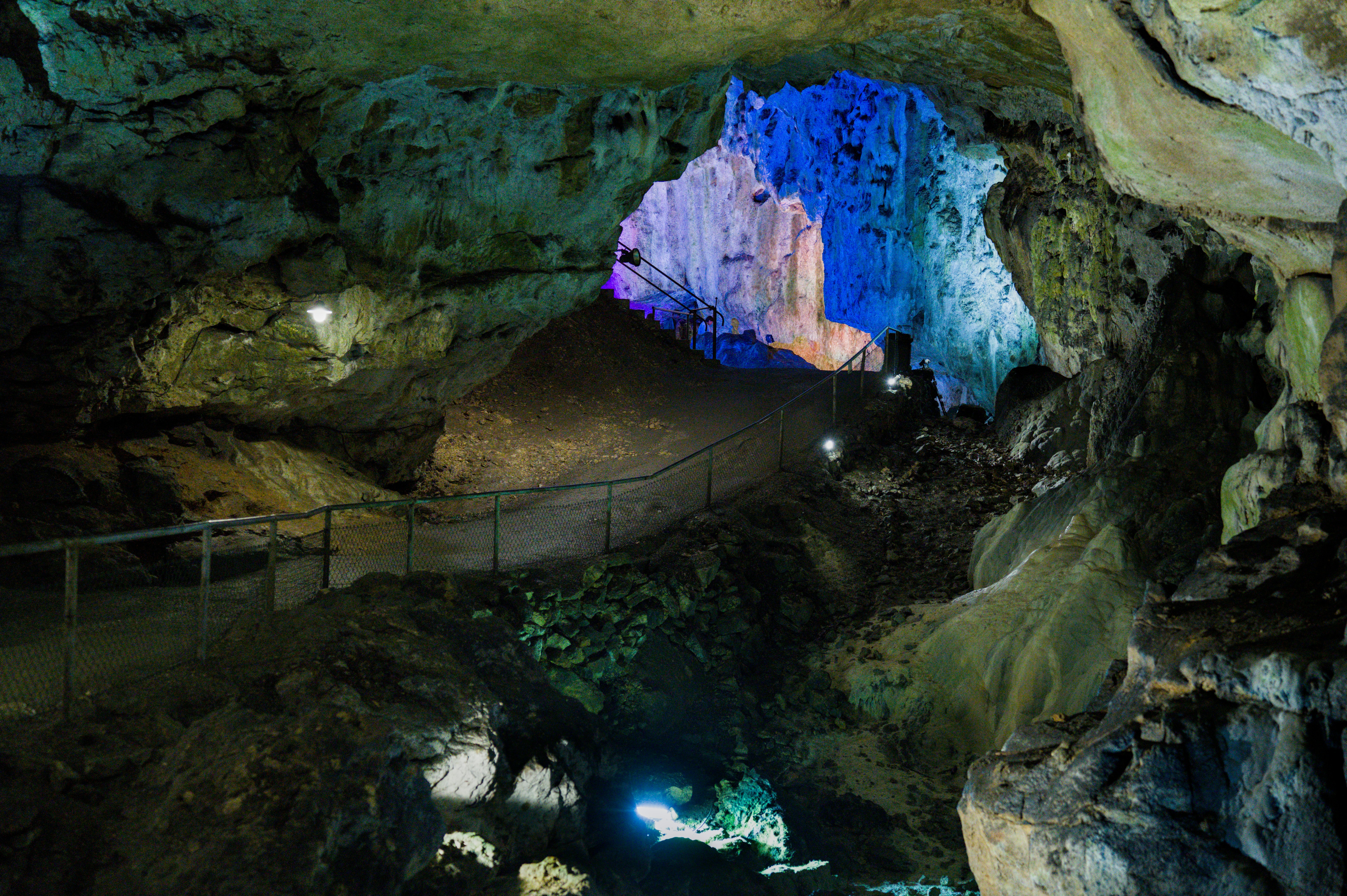 Illuminated cave interior with colorful lights highlighting natural rock formations.