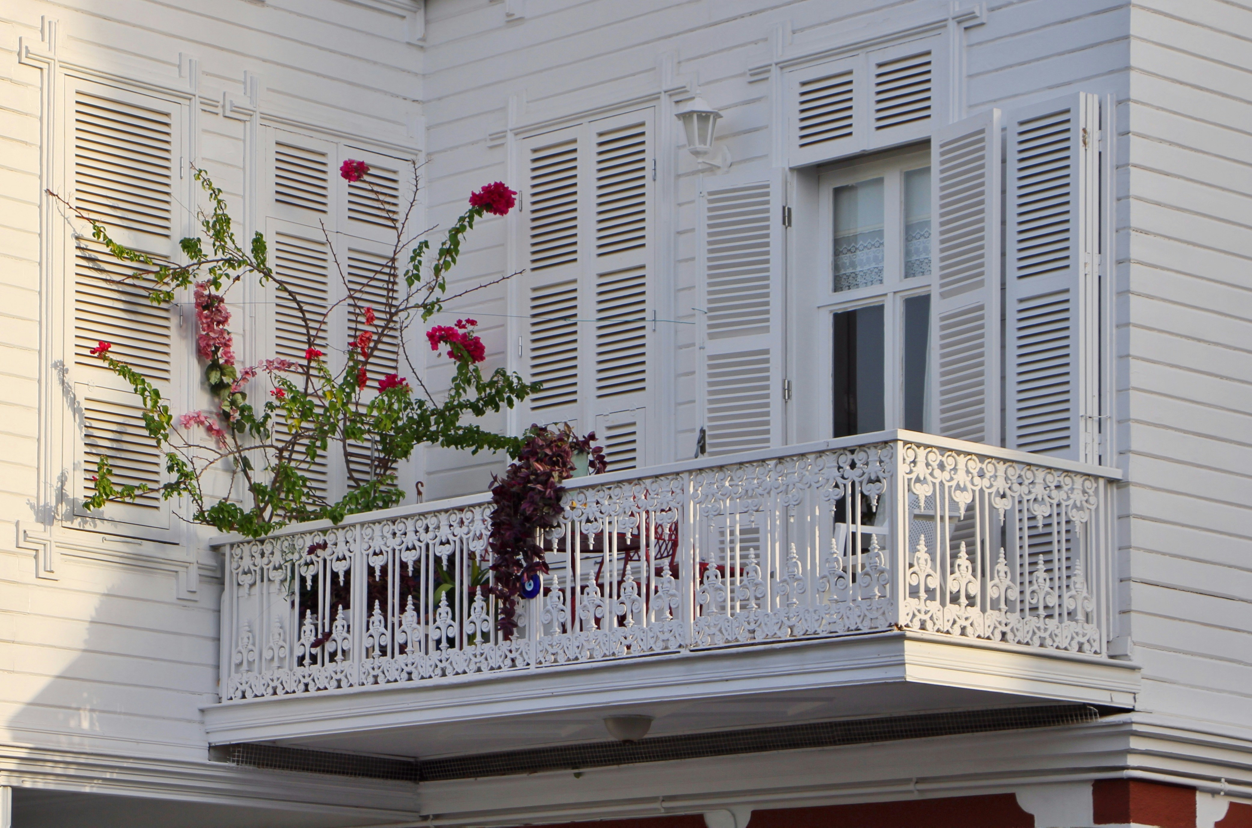 A white building with a balcony adorned with red flowers.