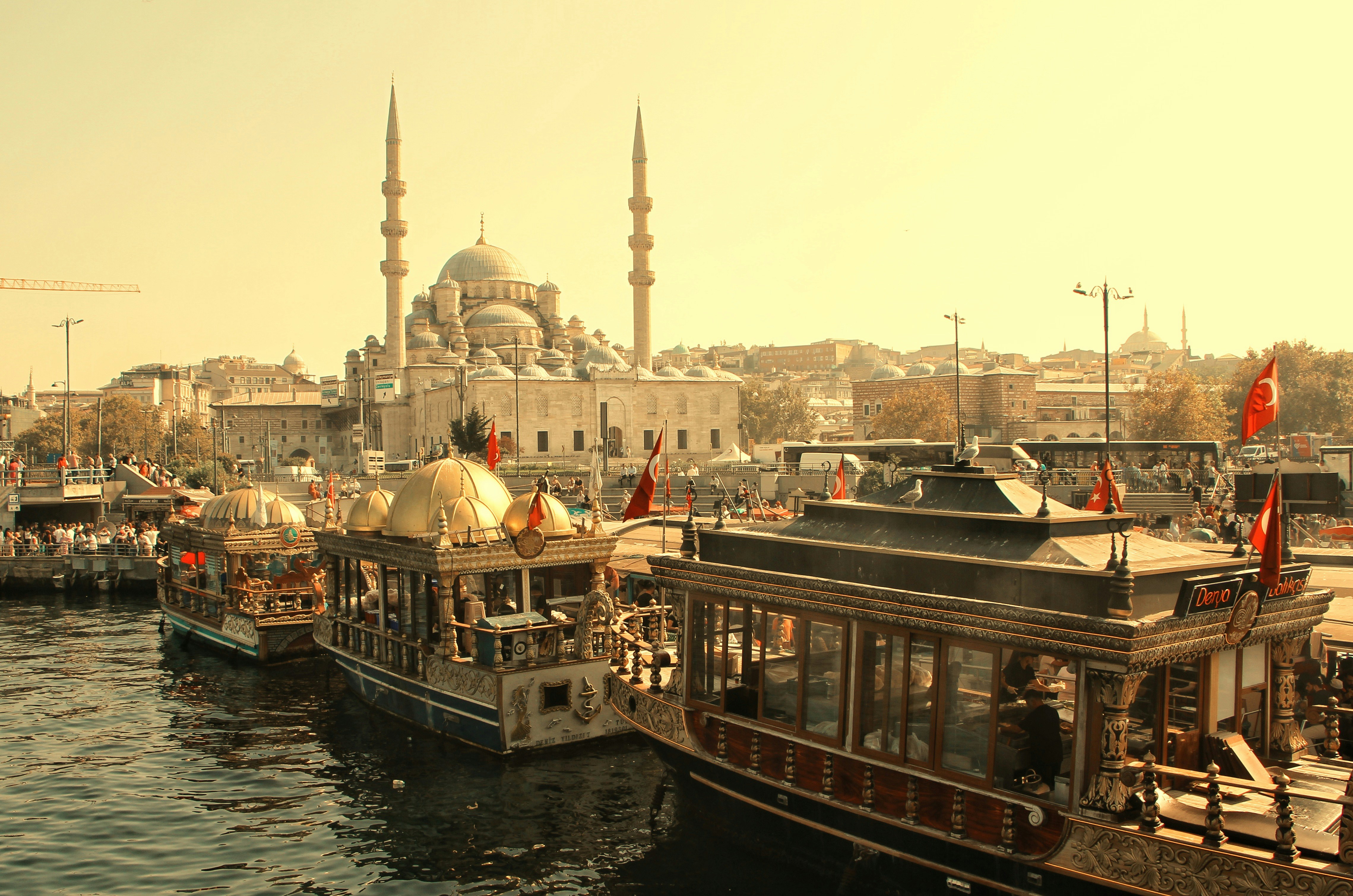 Boats docked near a grand mosque in a sunny city.