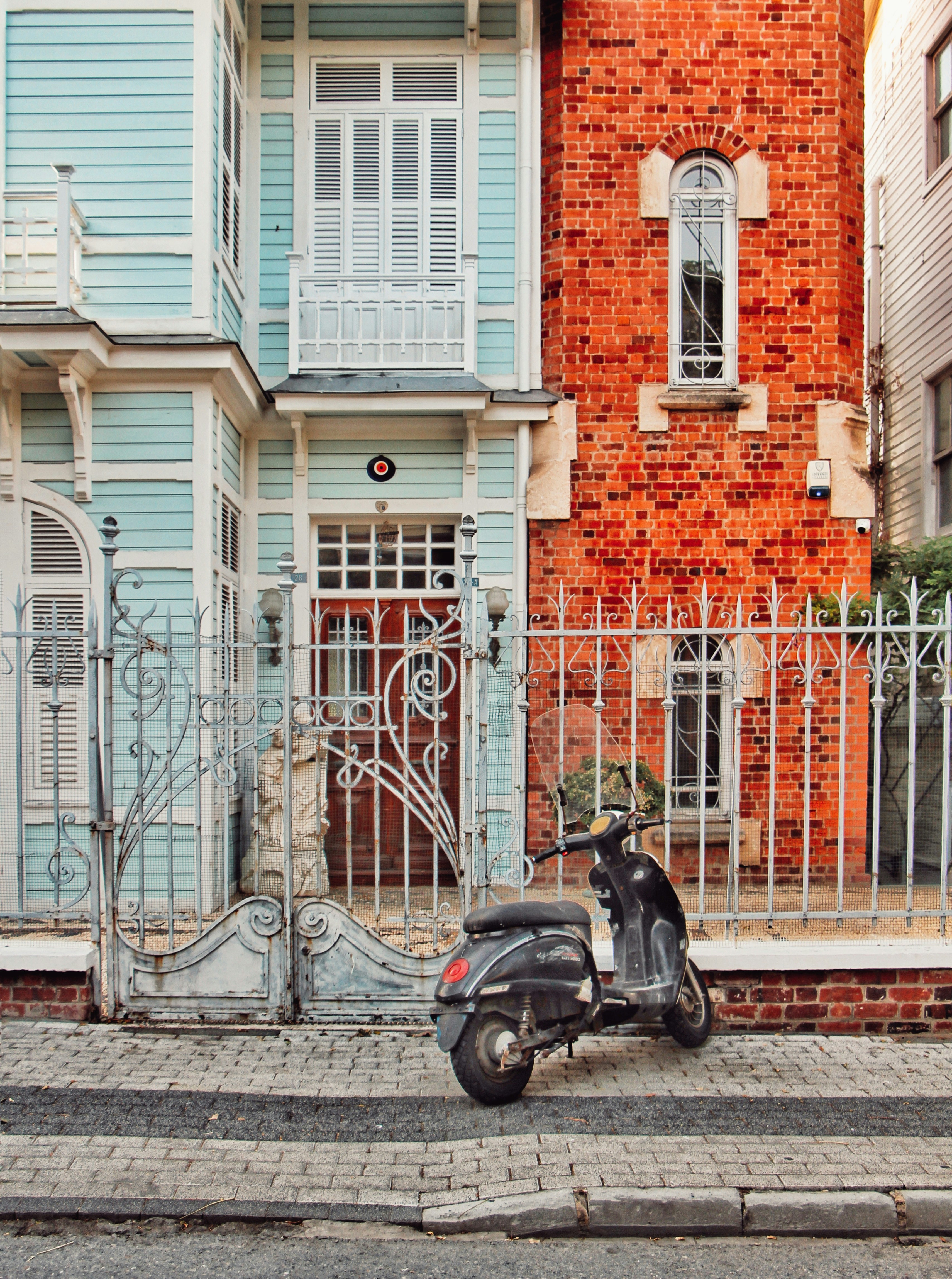 A black scooter parked before vibrant blue and red buildings.