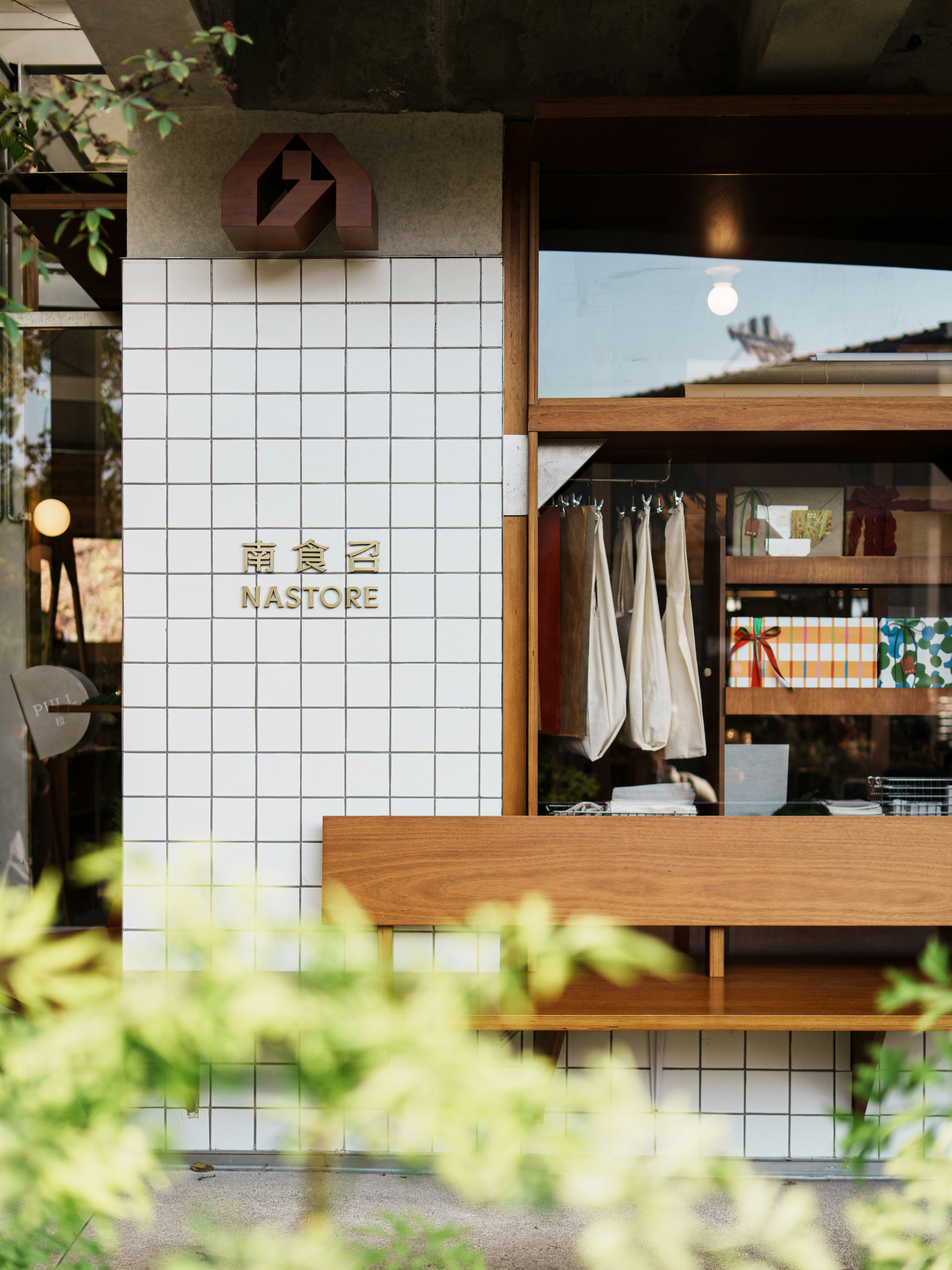 Nastore shop exterior with white tiles and a wooden window.