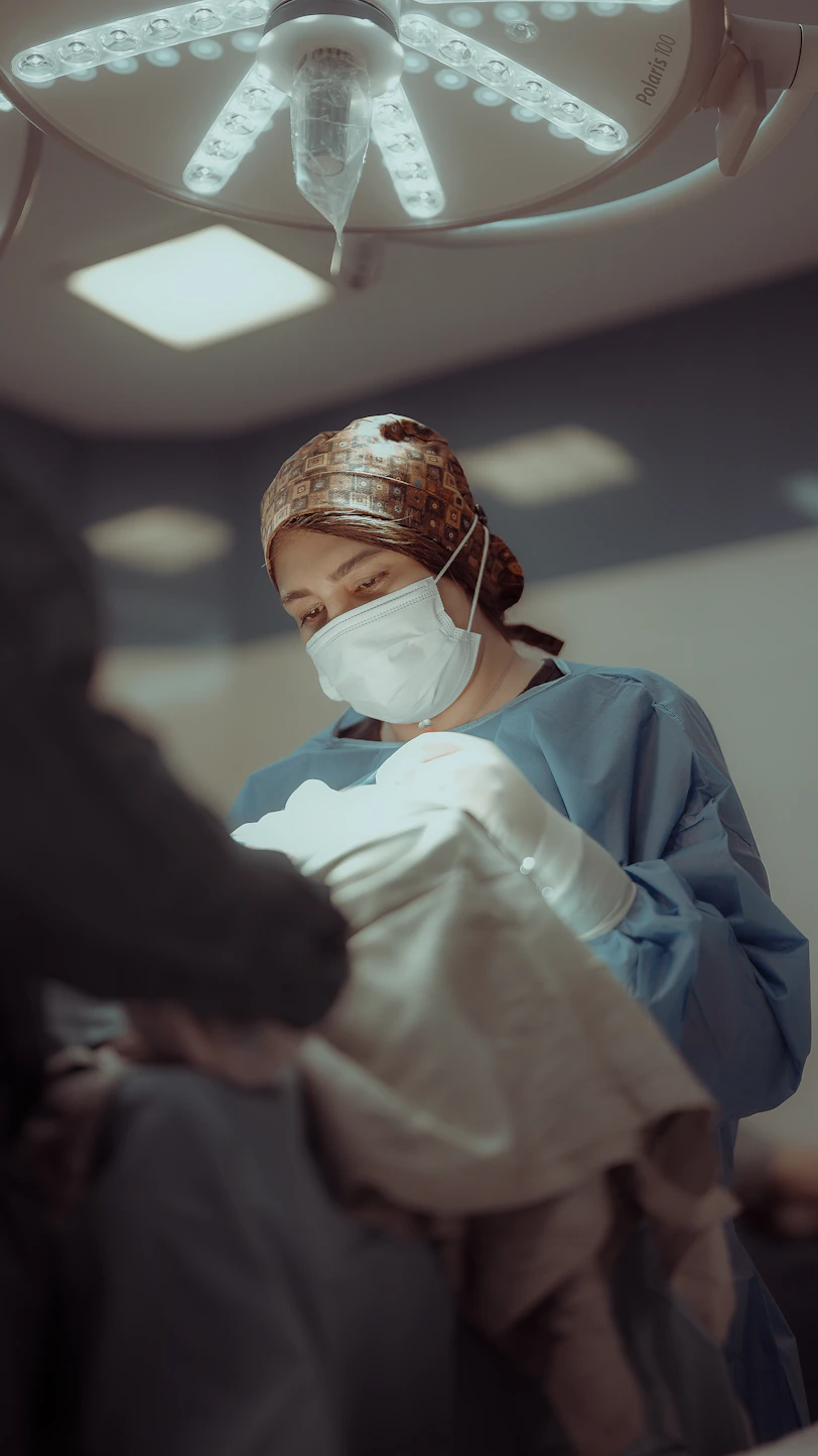 Female surgeon in scrubs and mask under operating room light