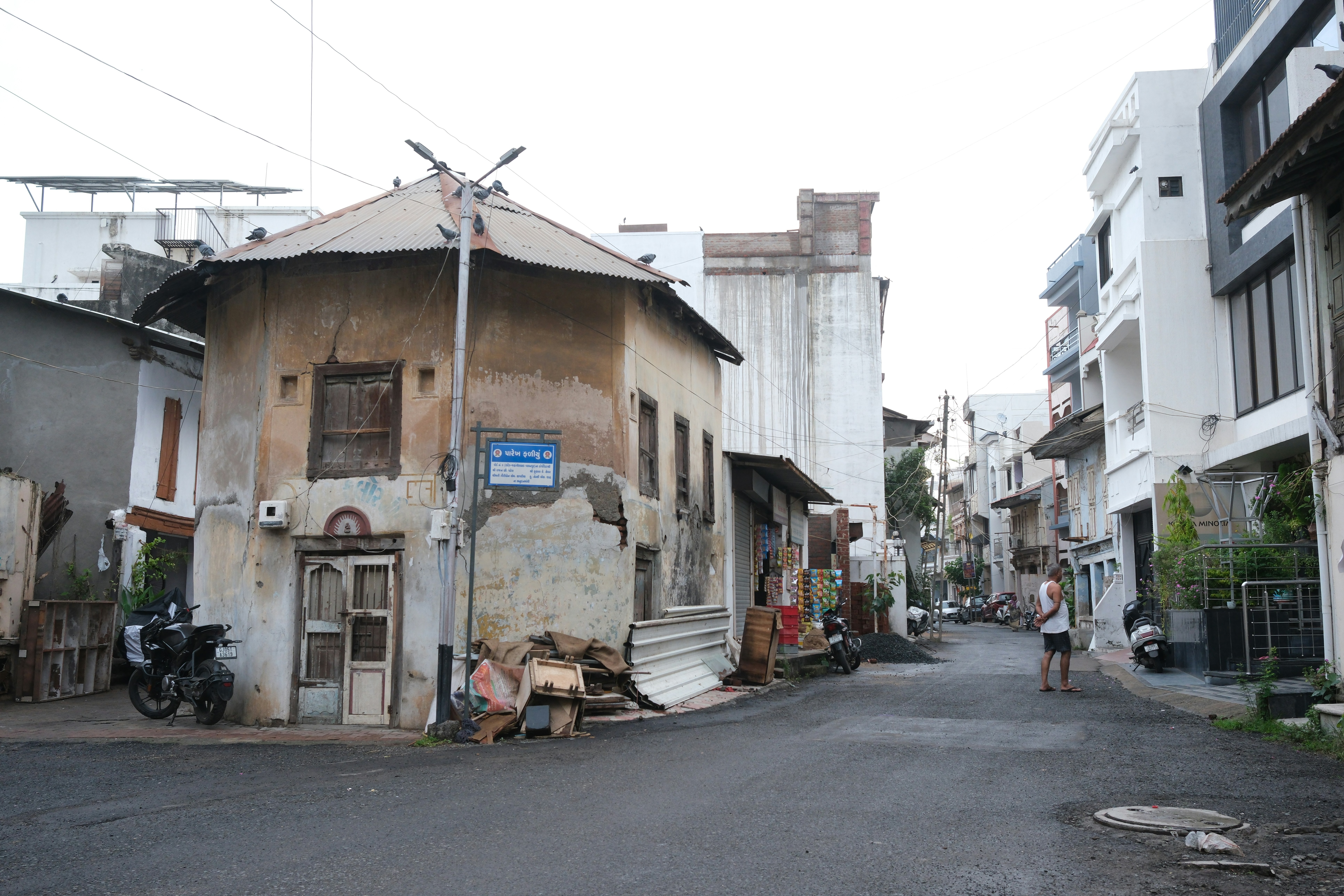 Dilapidated old building on a street with modern structures