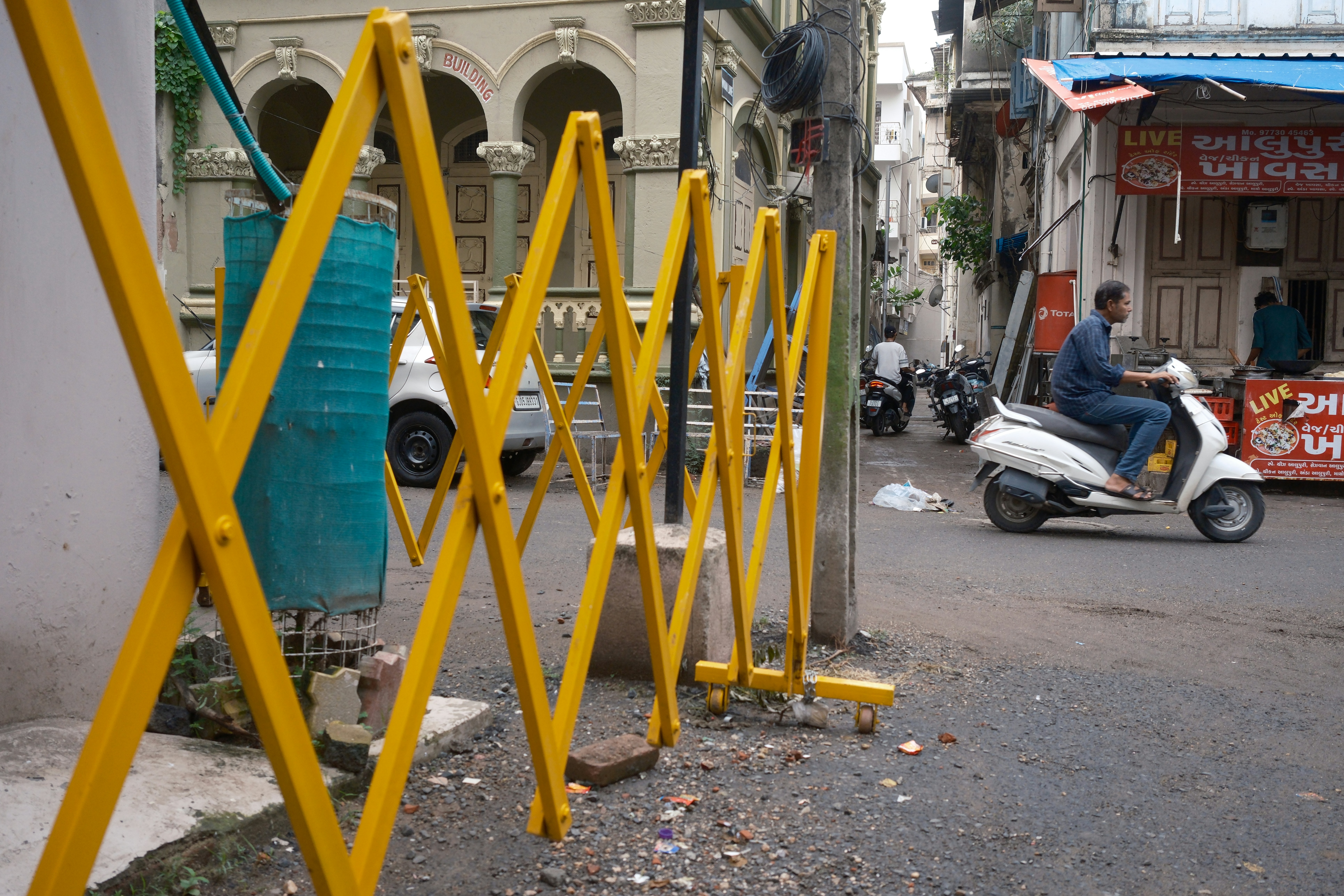 Yellow accordion barrier on a city street with a scooter