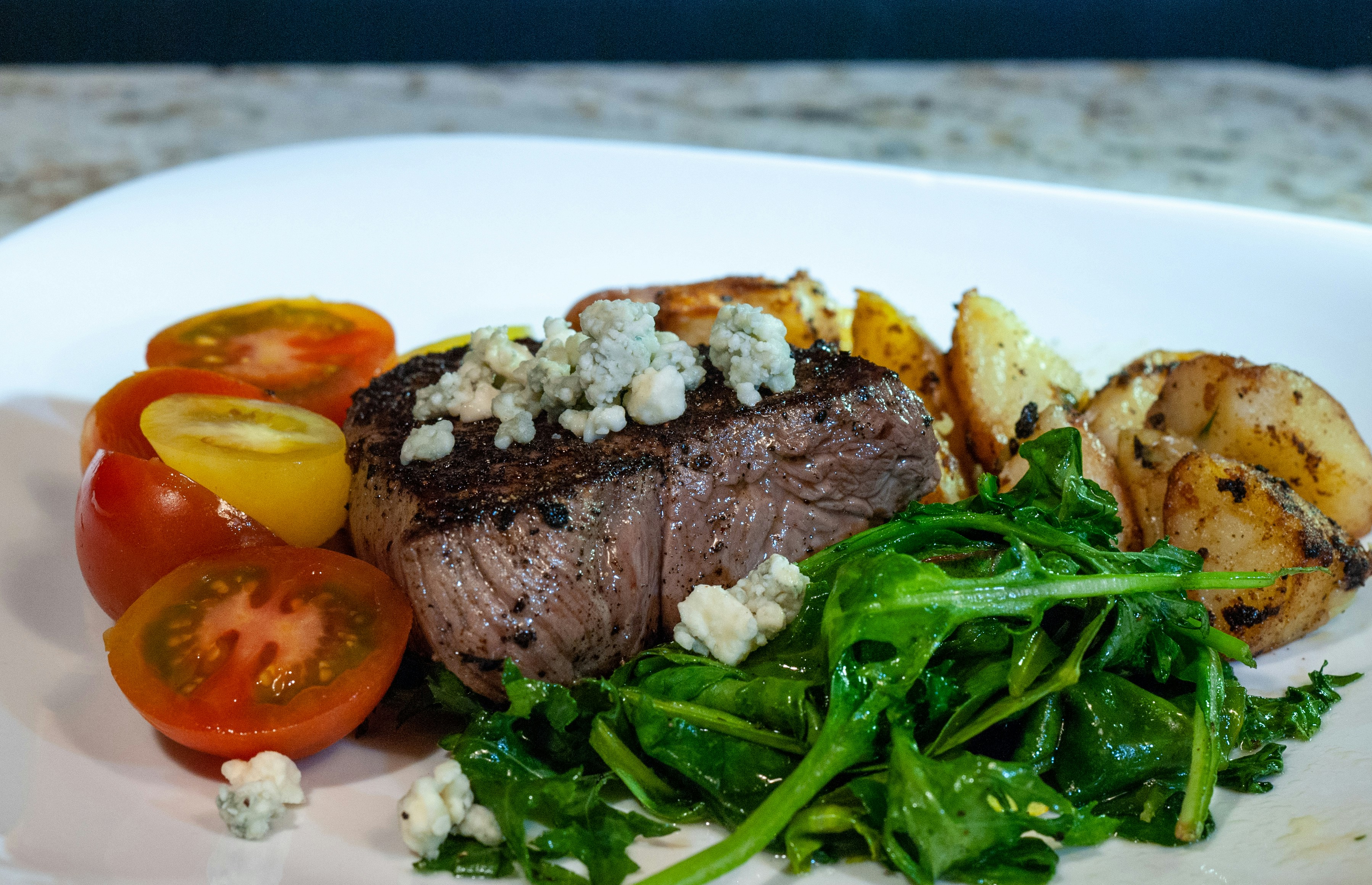 Gegrilltes Steak mit Blauschimmelkäse, Kartoffeln, Spinat und Tomaten.