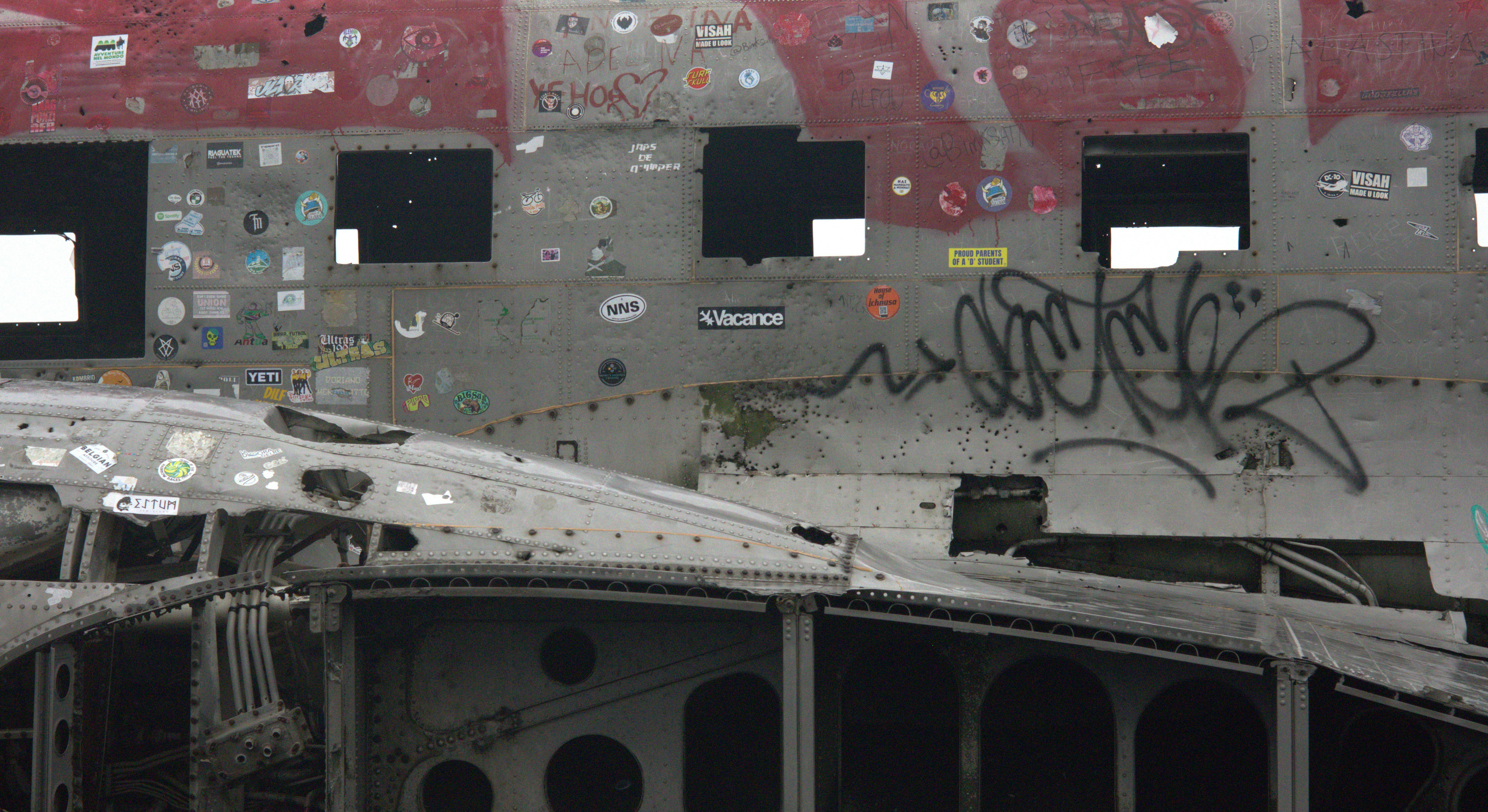 Mur métallique usé avec graffitis, autocollants et ouvertures de fenêtres sombres